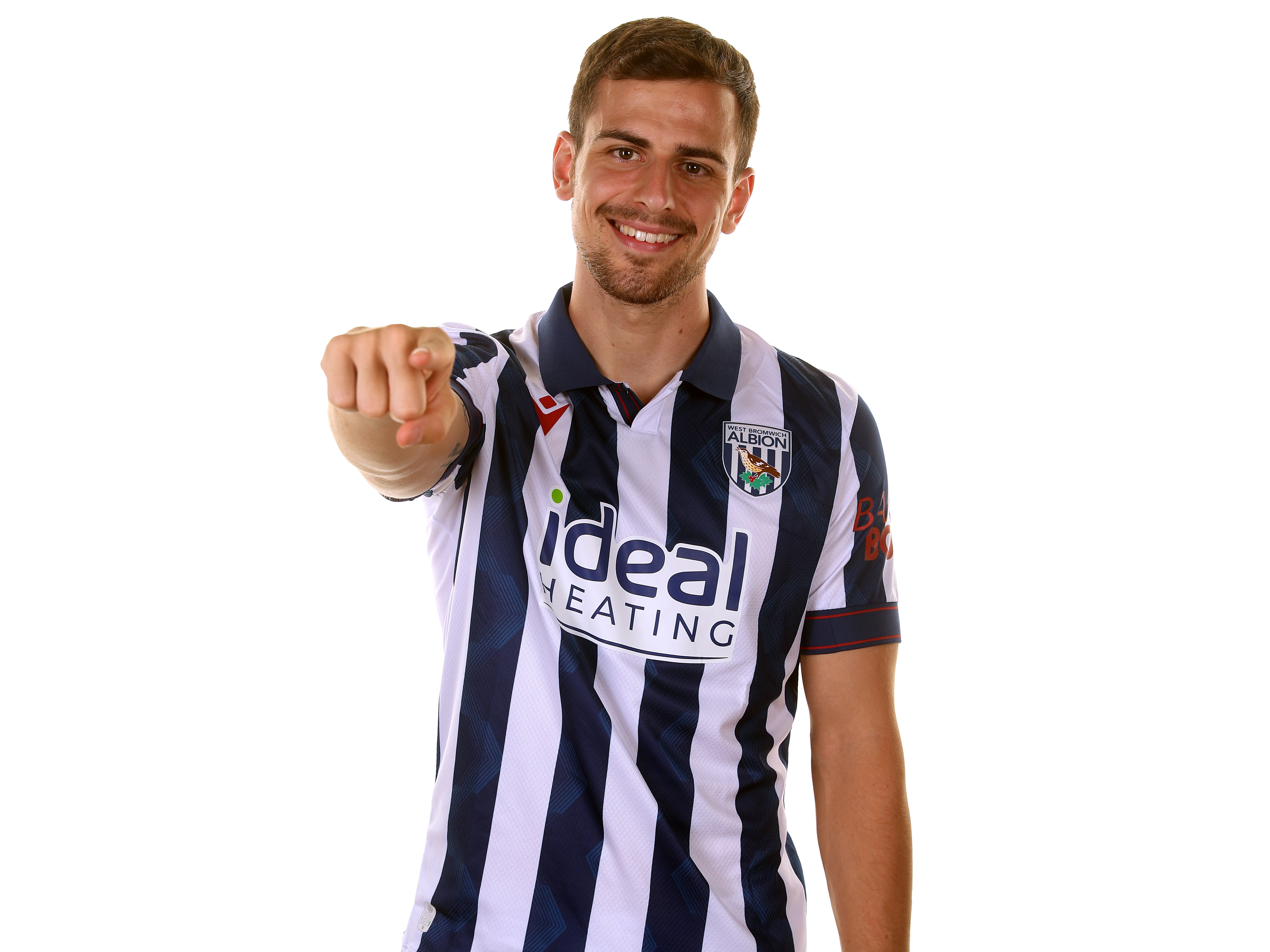 Jayson Molumby pointing at the camera and smiling while wearing a home shirt 