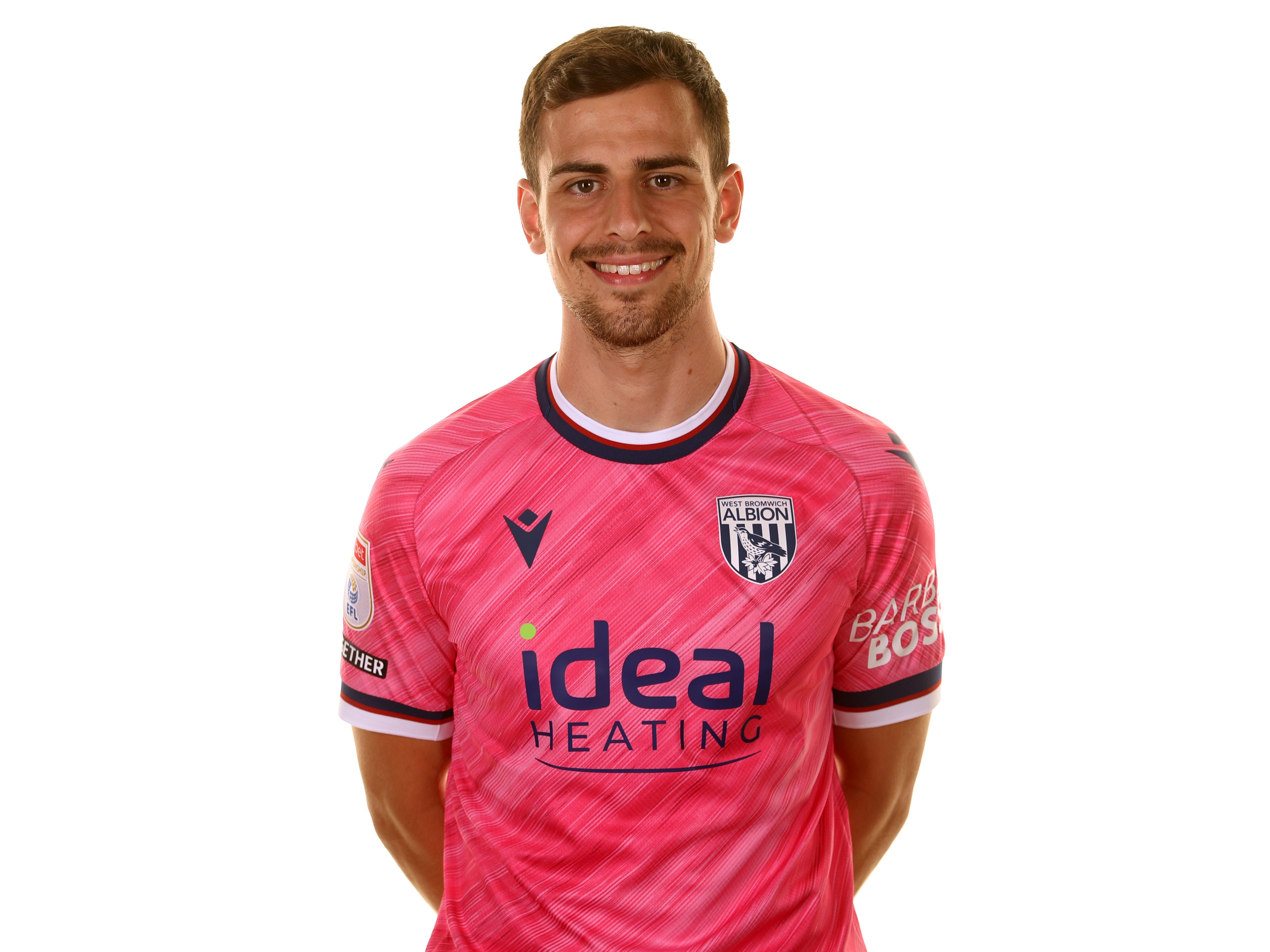 Jayson Molumby smiling at the camera wearing the pink away shirt 