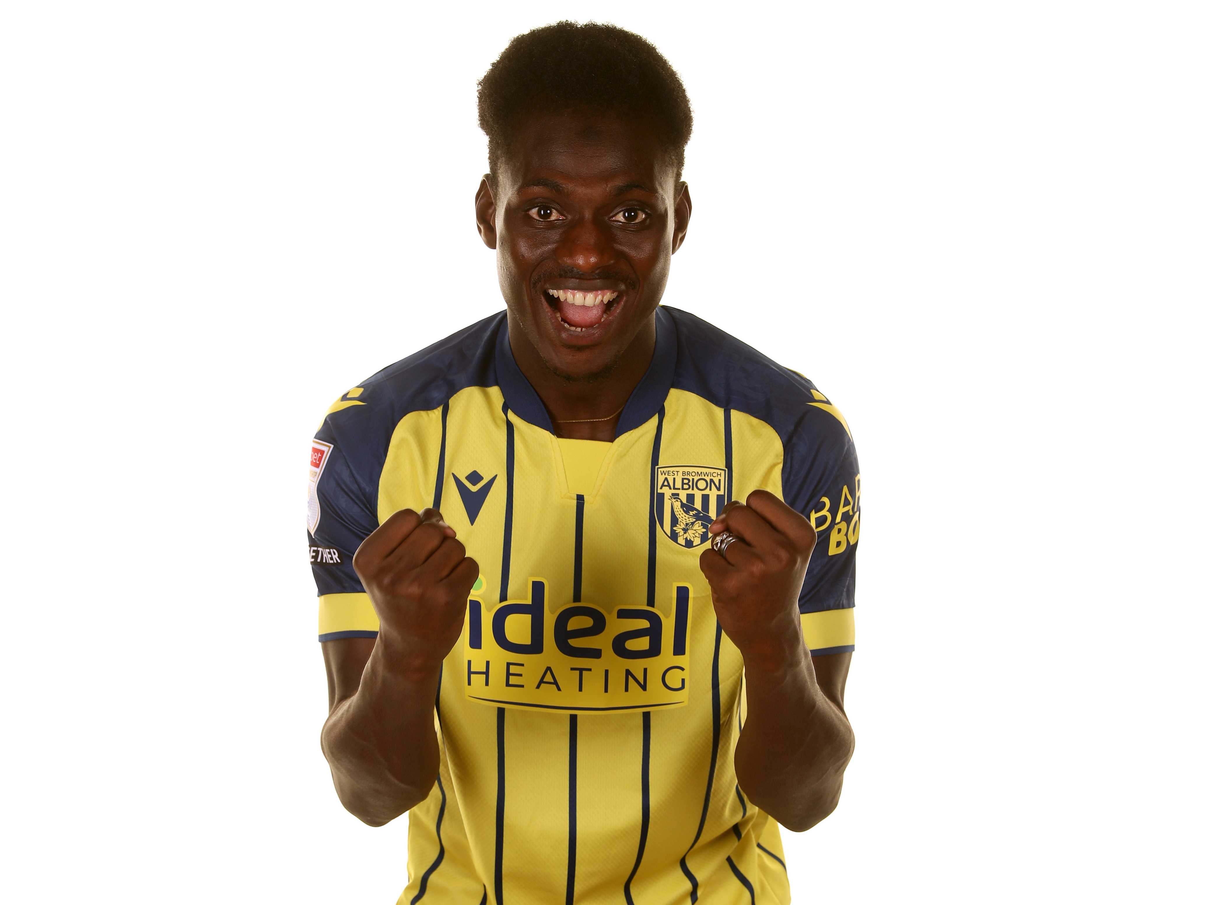 Ousmane Diakité celebrating at the camera with fists clenched while wearing the yellow away shirt 