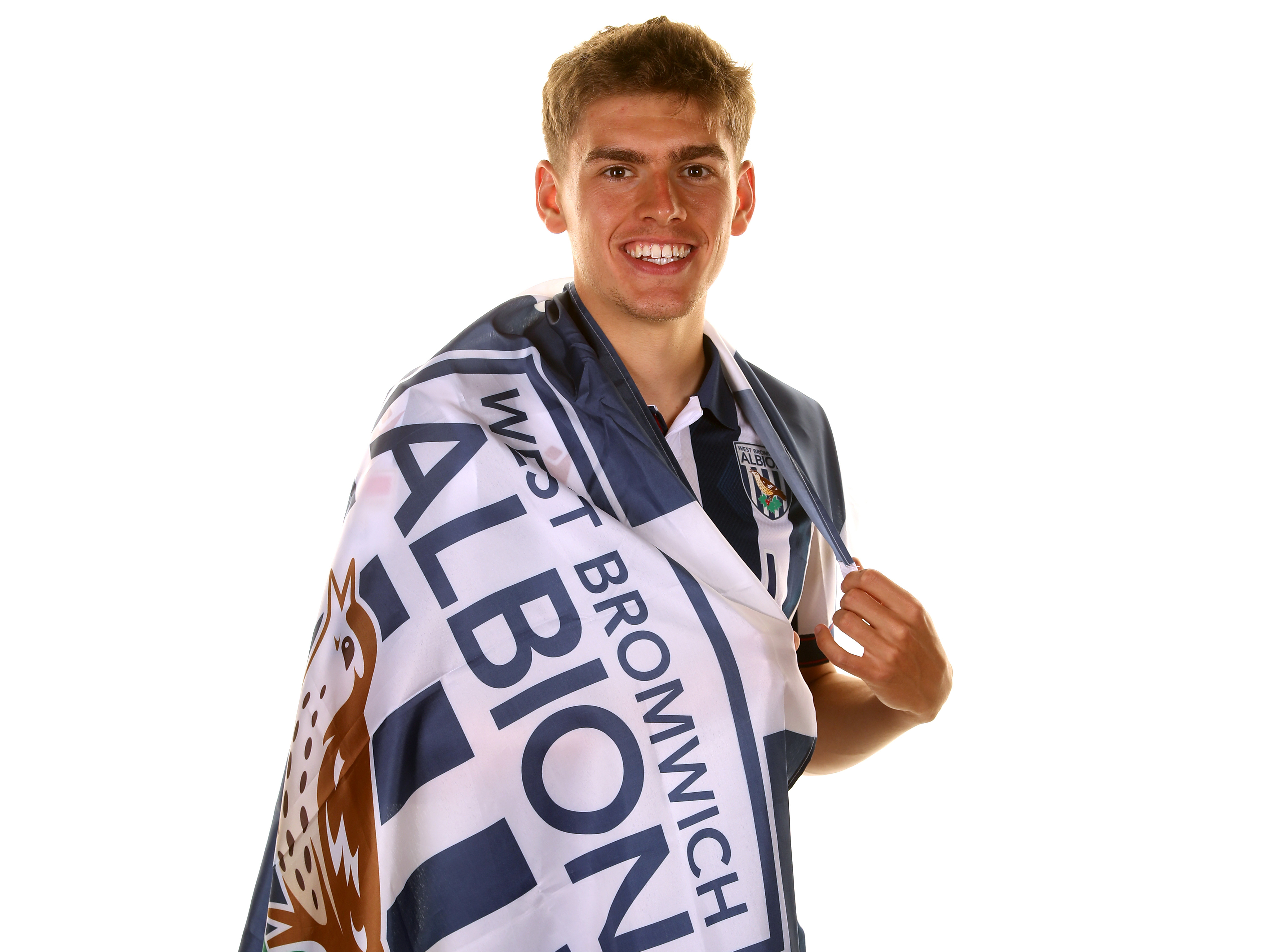 Tom Fellows wrapped in a WBA flag while wearing a home shirt smiling at the camera 