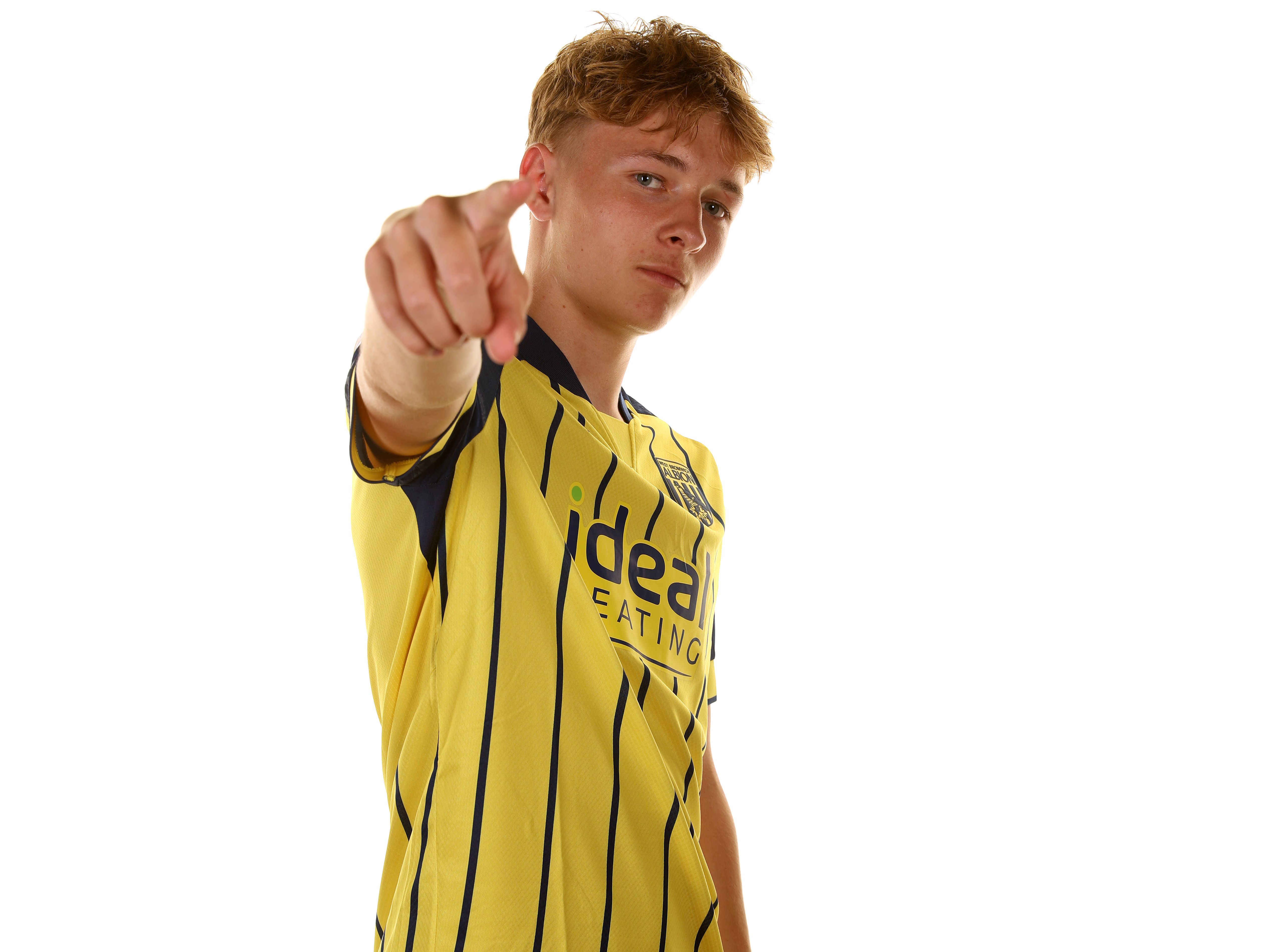 Ollie Bostock pointing at the camera while wearing the yellow away shirt 