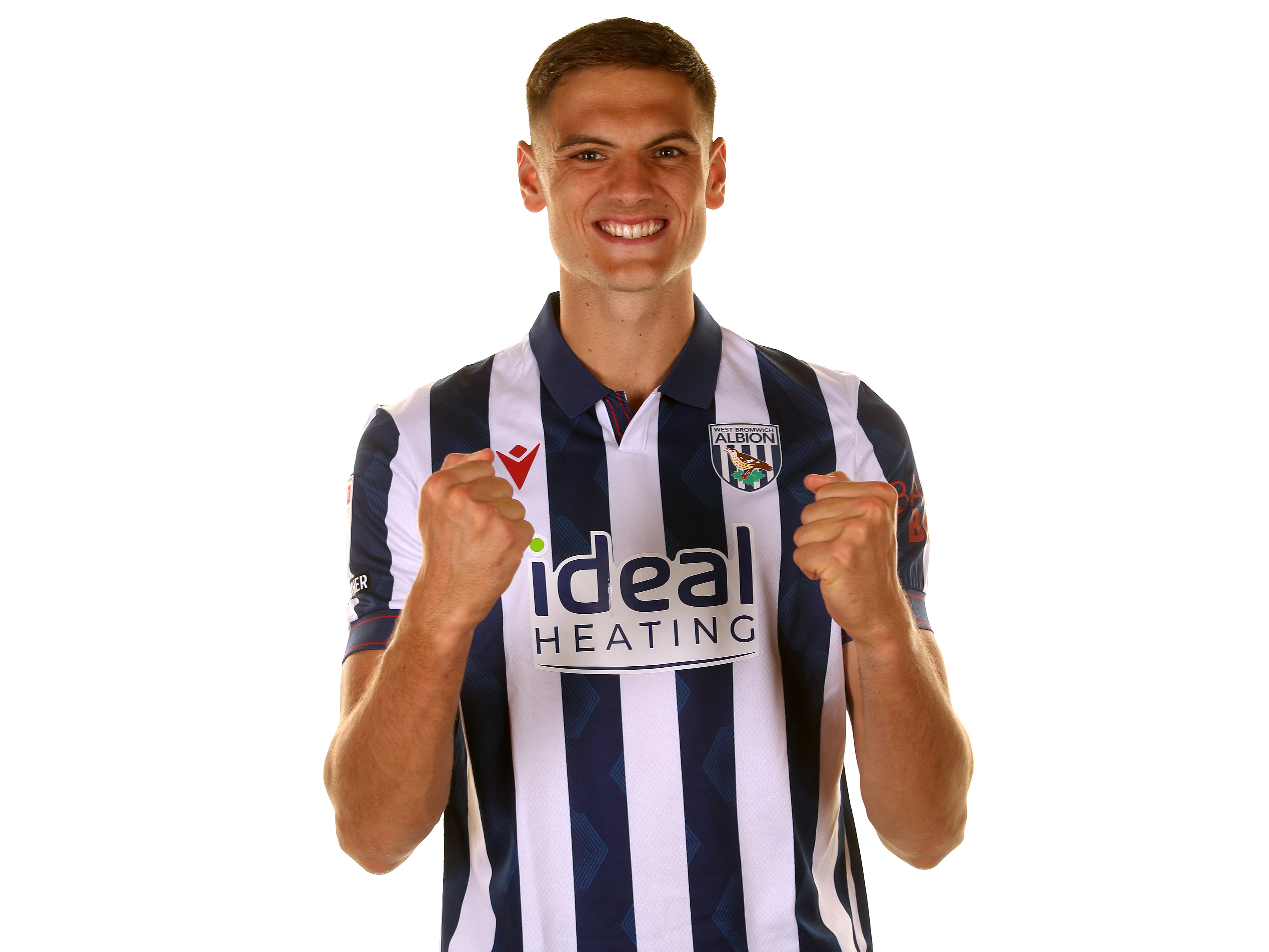 Caleb Taylor smiling at the camera in a home shirt with his fists clenched 