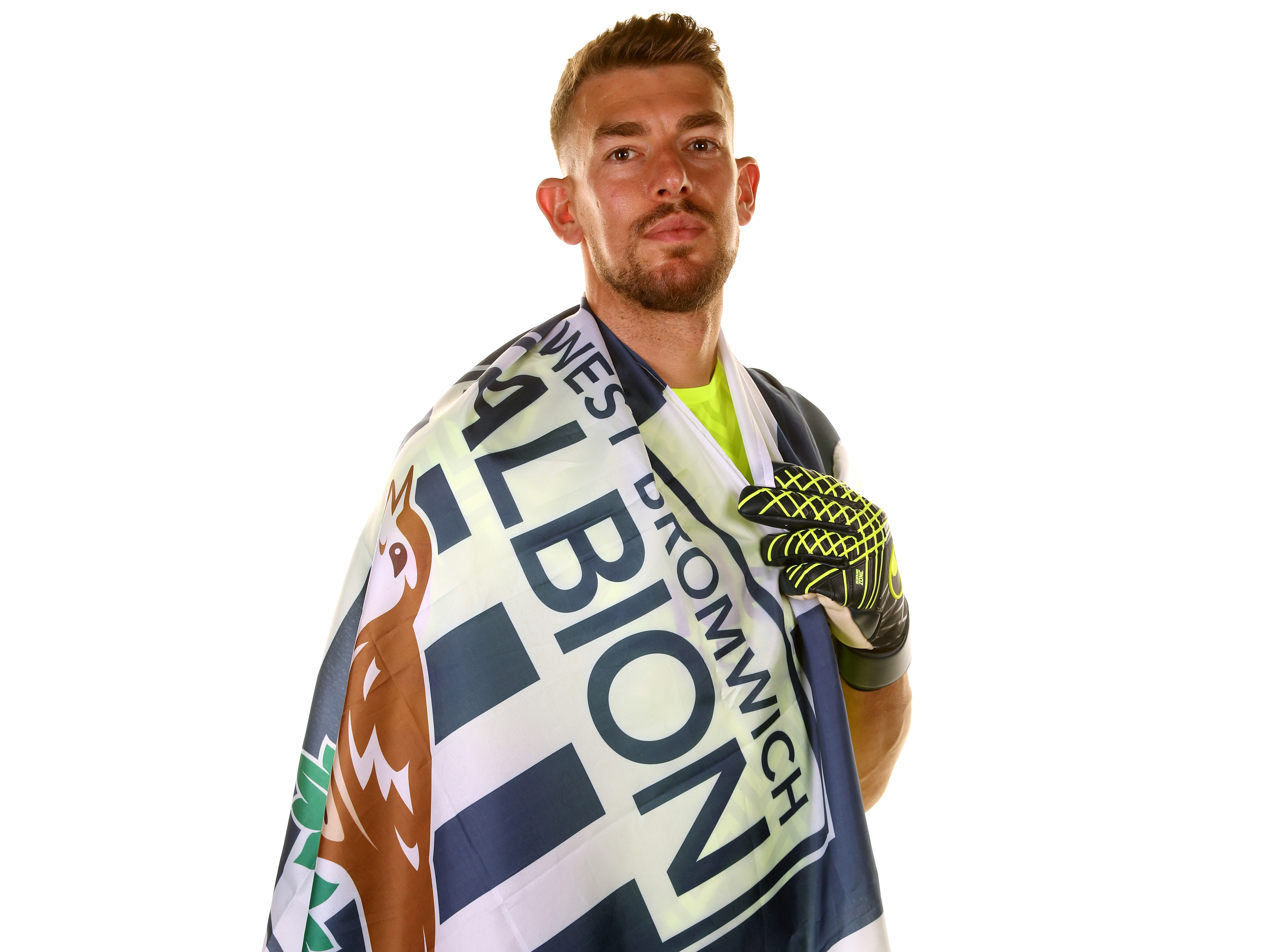 Alex Palmer looking at the camera while wrapped in an Albion flag