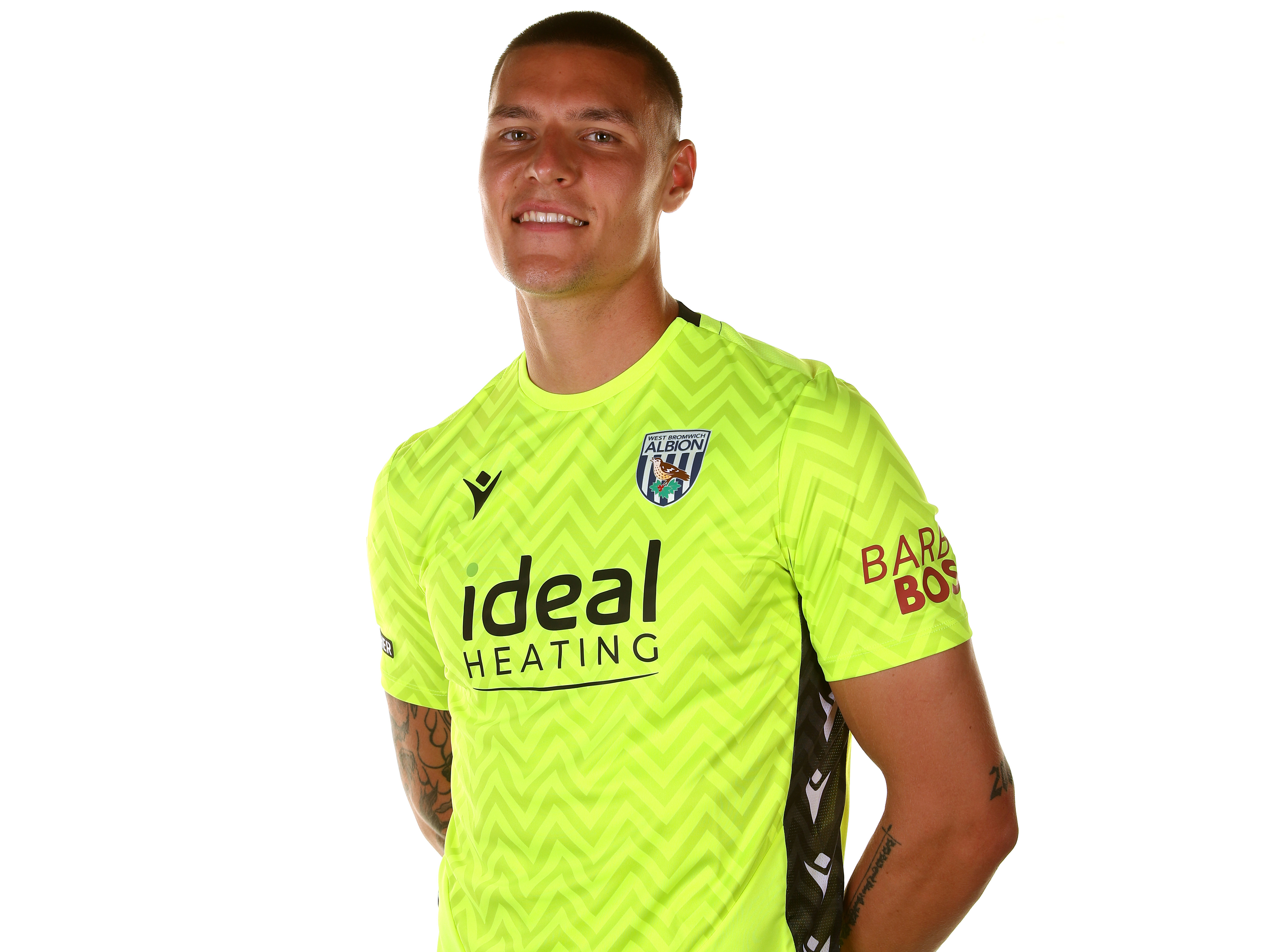 Ted Cann smiling at the camera while wearing the yellow goalkeeper kit 