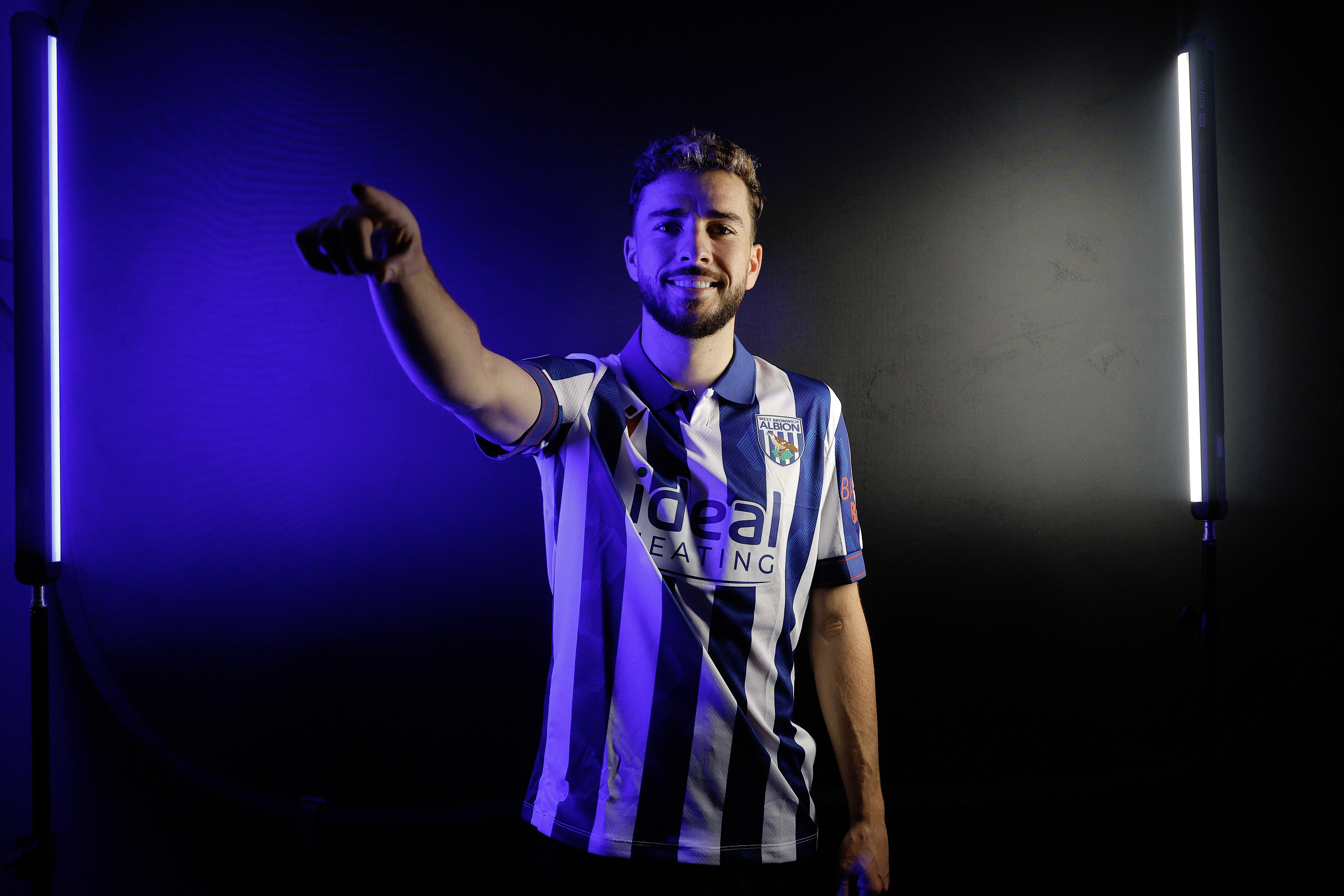 Mikey Johnston pointing at the camera while wearing a home shirt and stood in a TV studio 