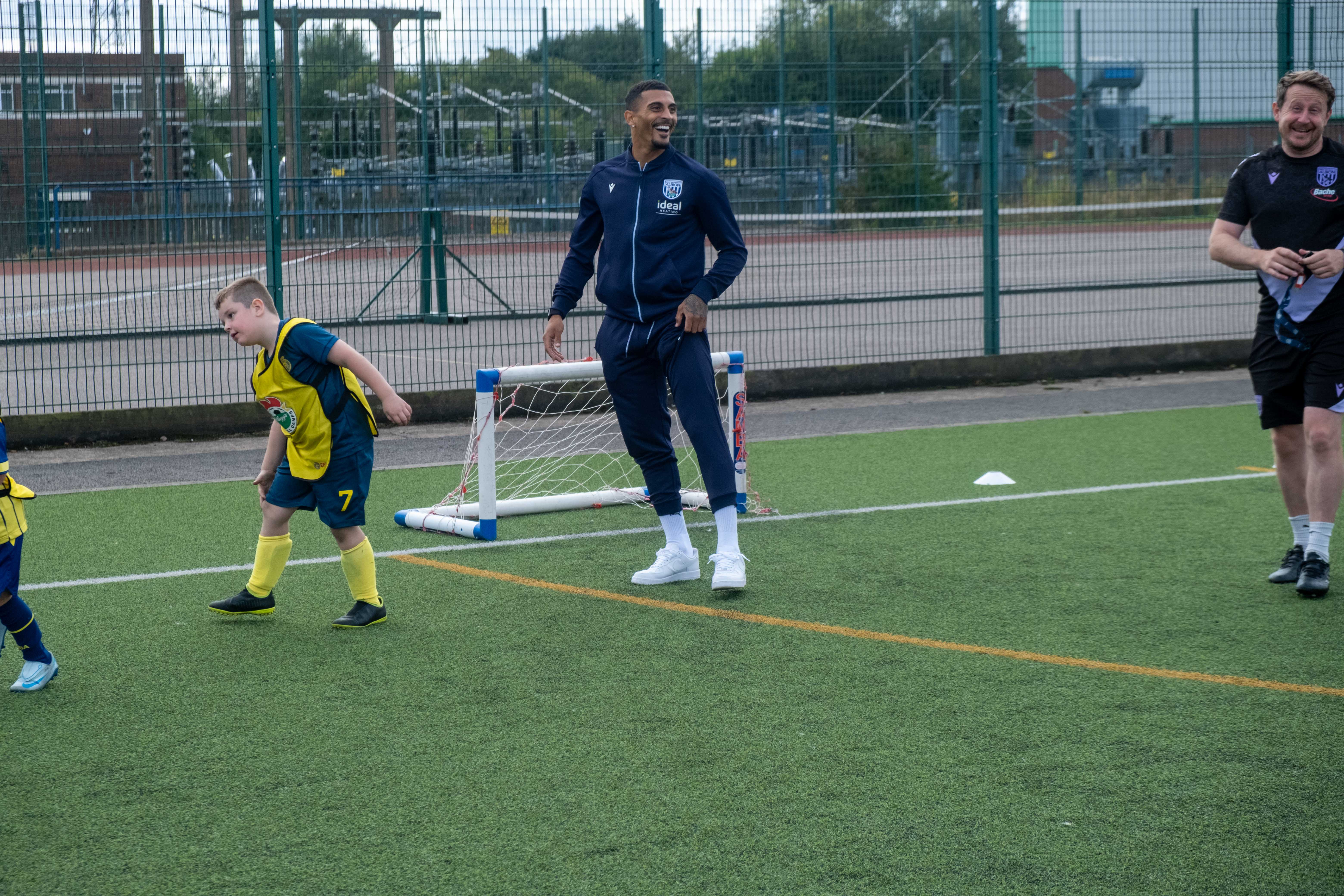 Karlan Grant plays football with camp participants.