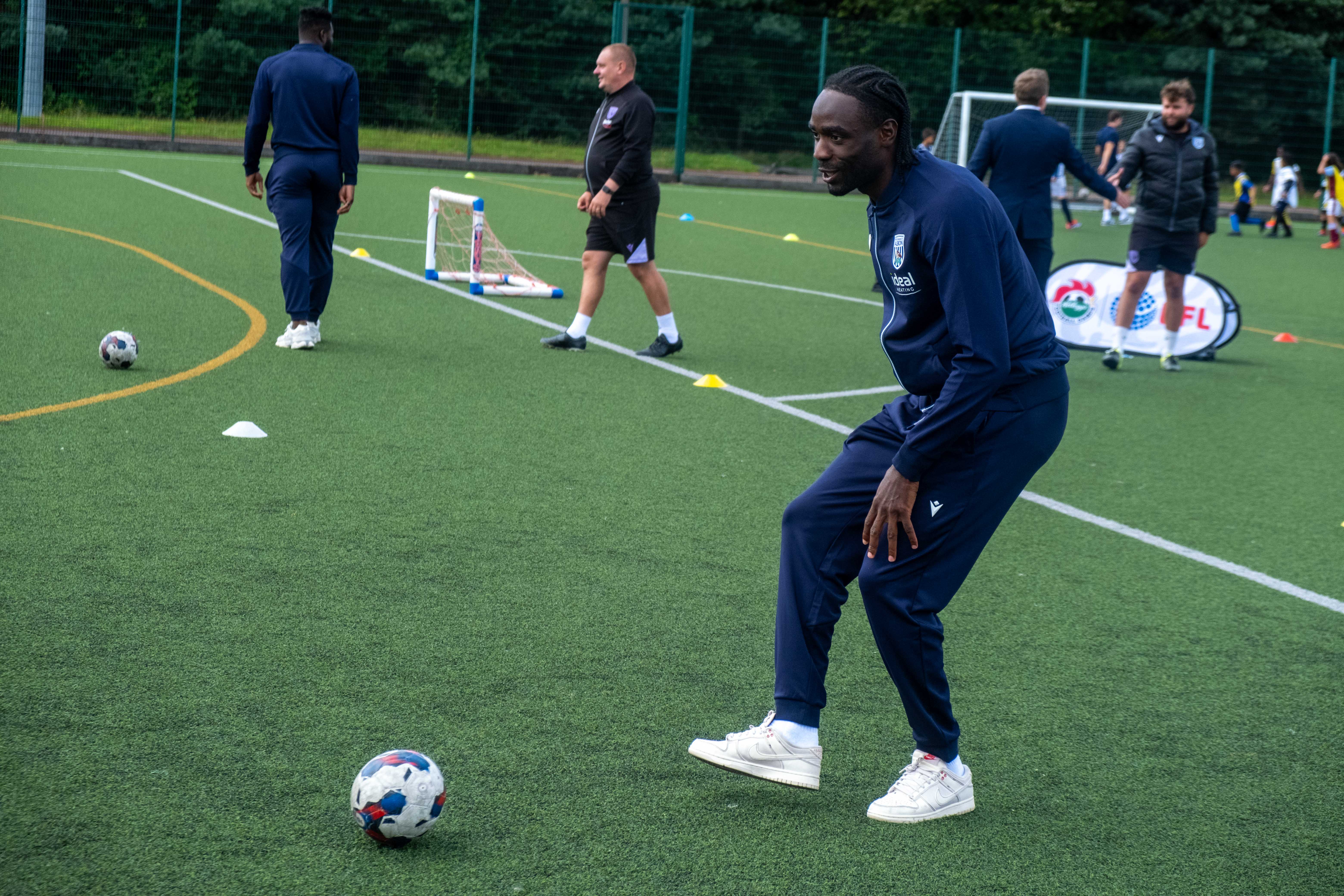 Devante Cole plays football with camp participants.