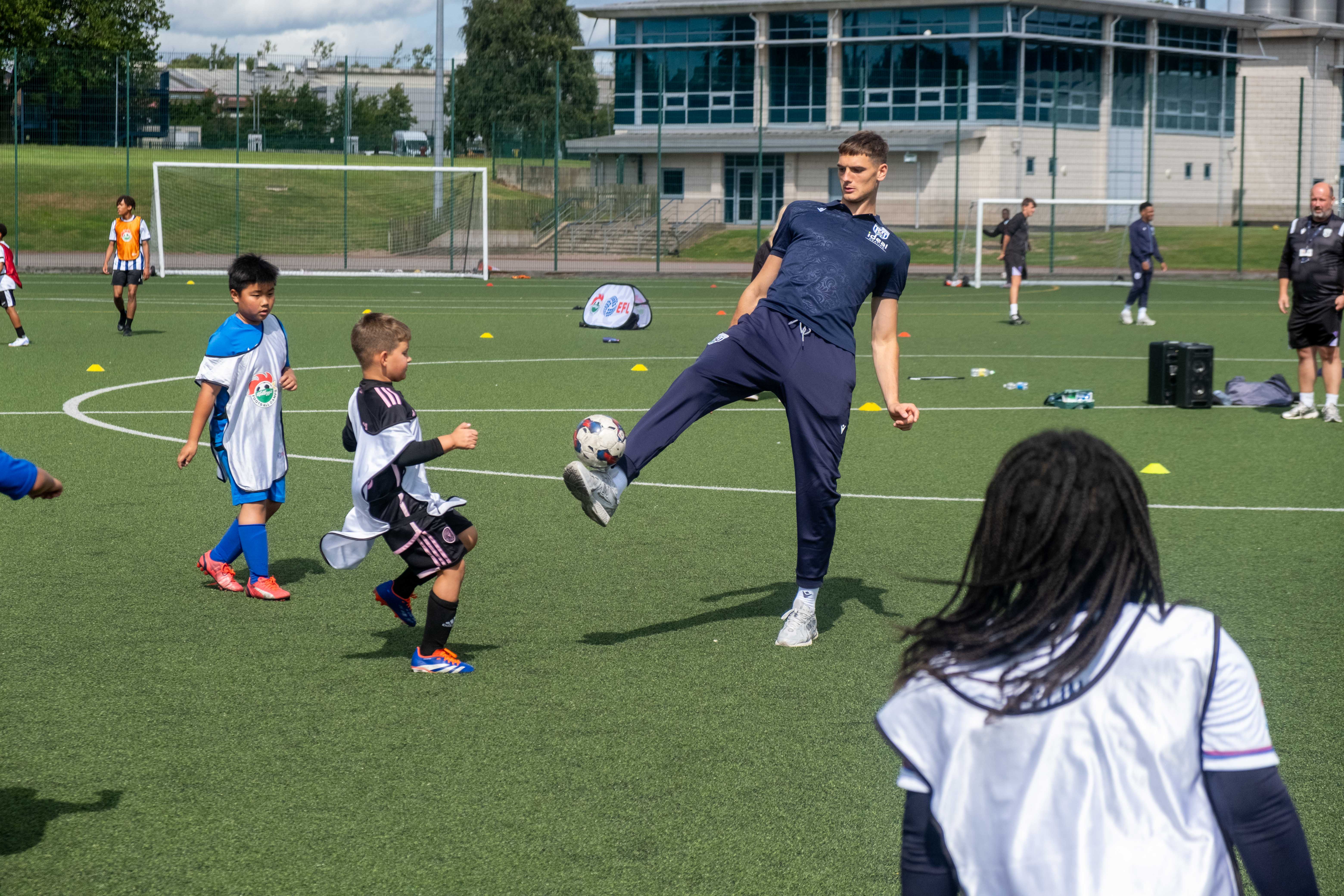 Caleb Taylor plays football with camp participants.