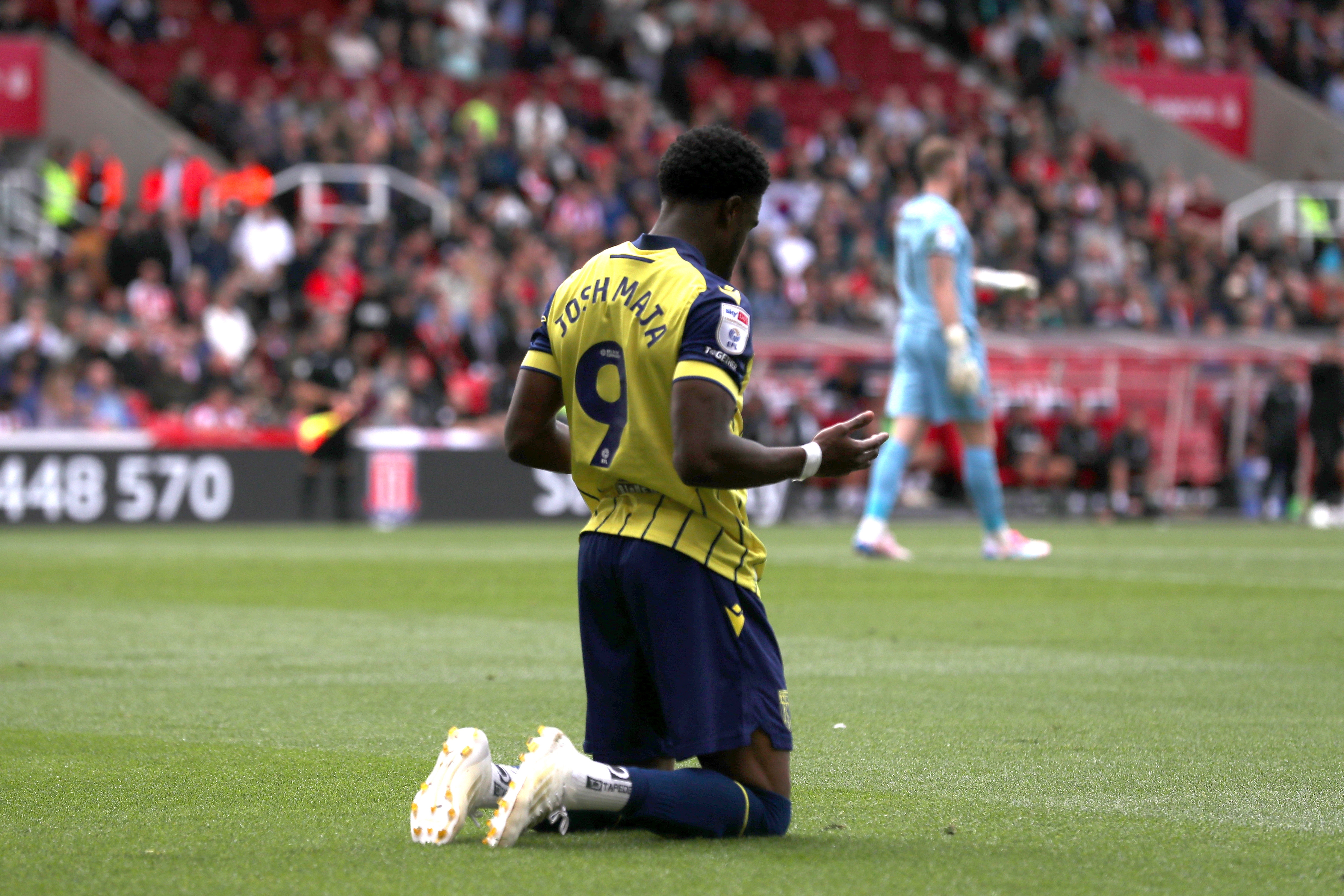 Josh Maja on his knees celebrating his goal at Stoke in the away shirt 