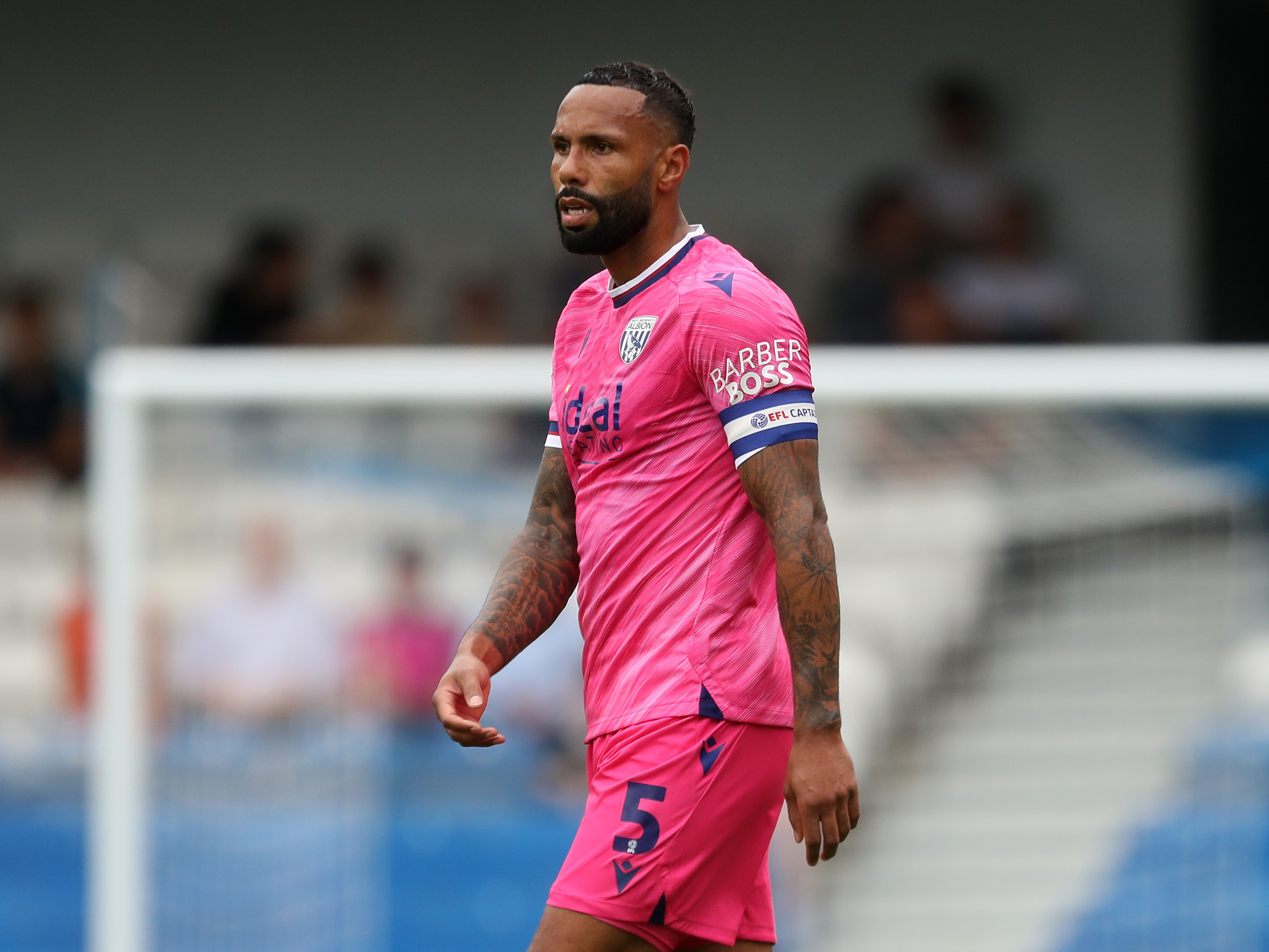 Kyle Bartley in action for Albion at QPR wearing a pink kit and a captain's armband 