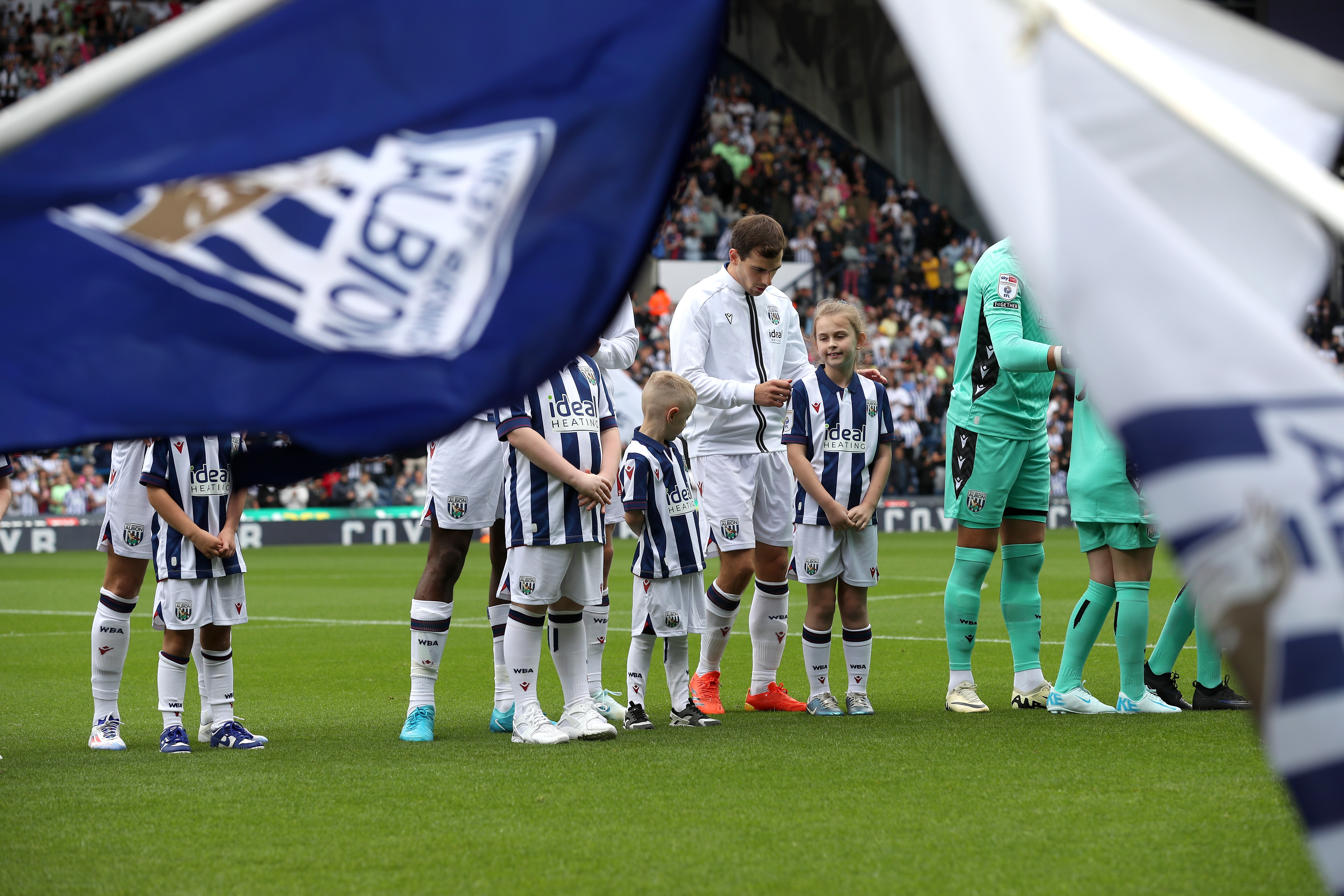 Jayson Molumby lining up with mascot on the pitch before the Leeds game 