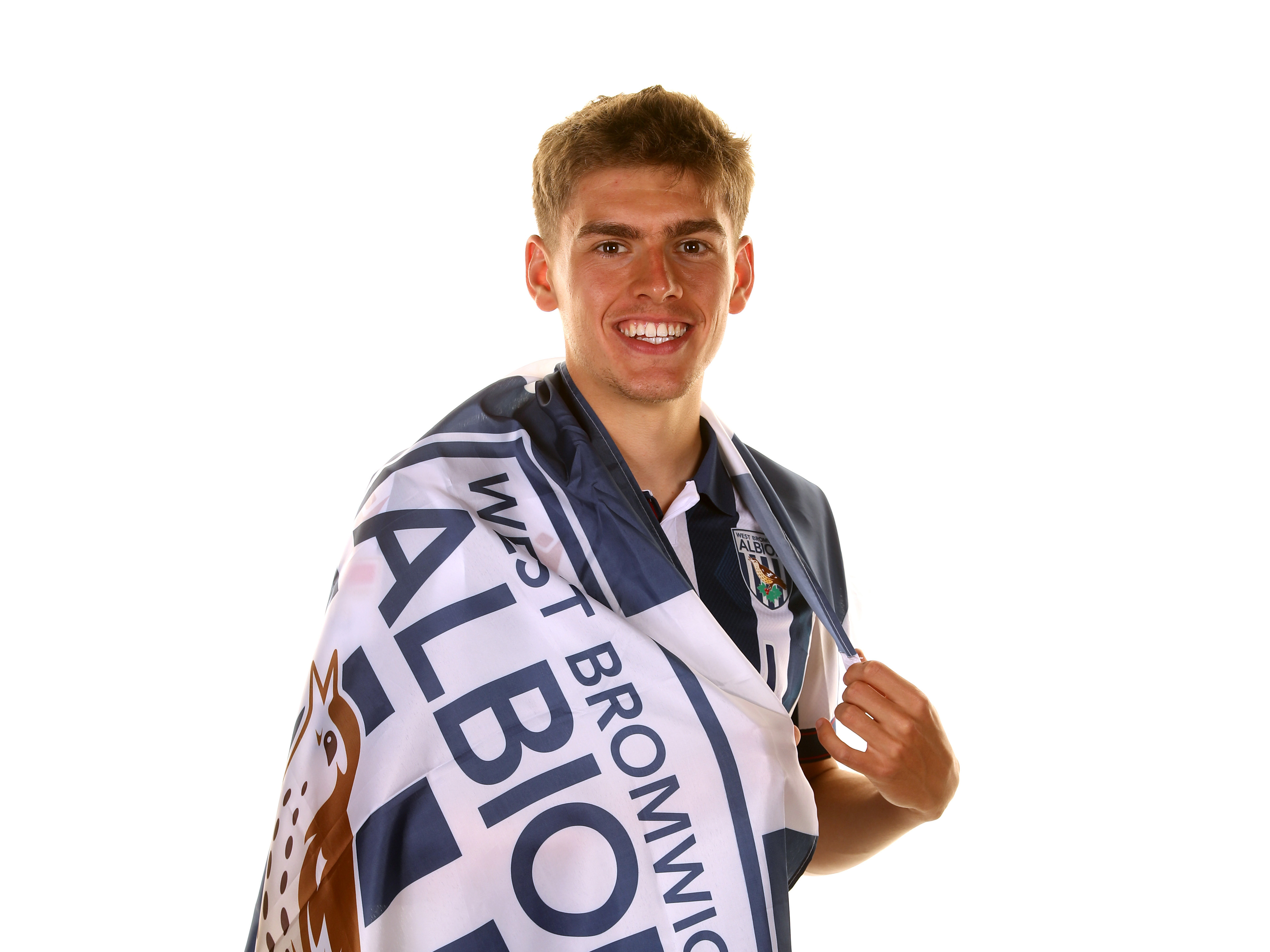 Tom Fellows smiling at the camera while wrapped in a WBA flag and the home shirt 