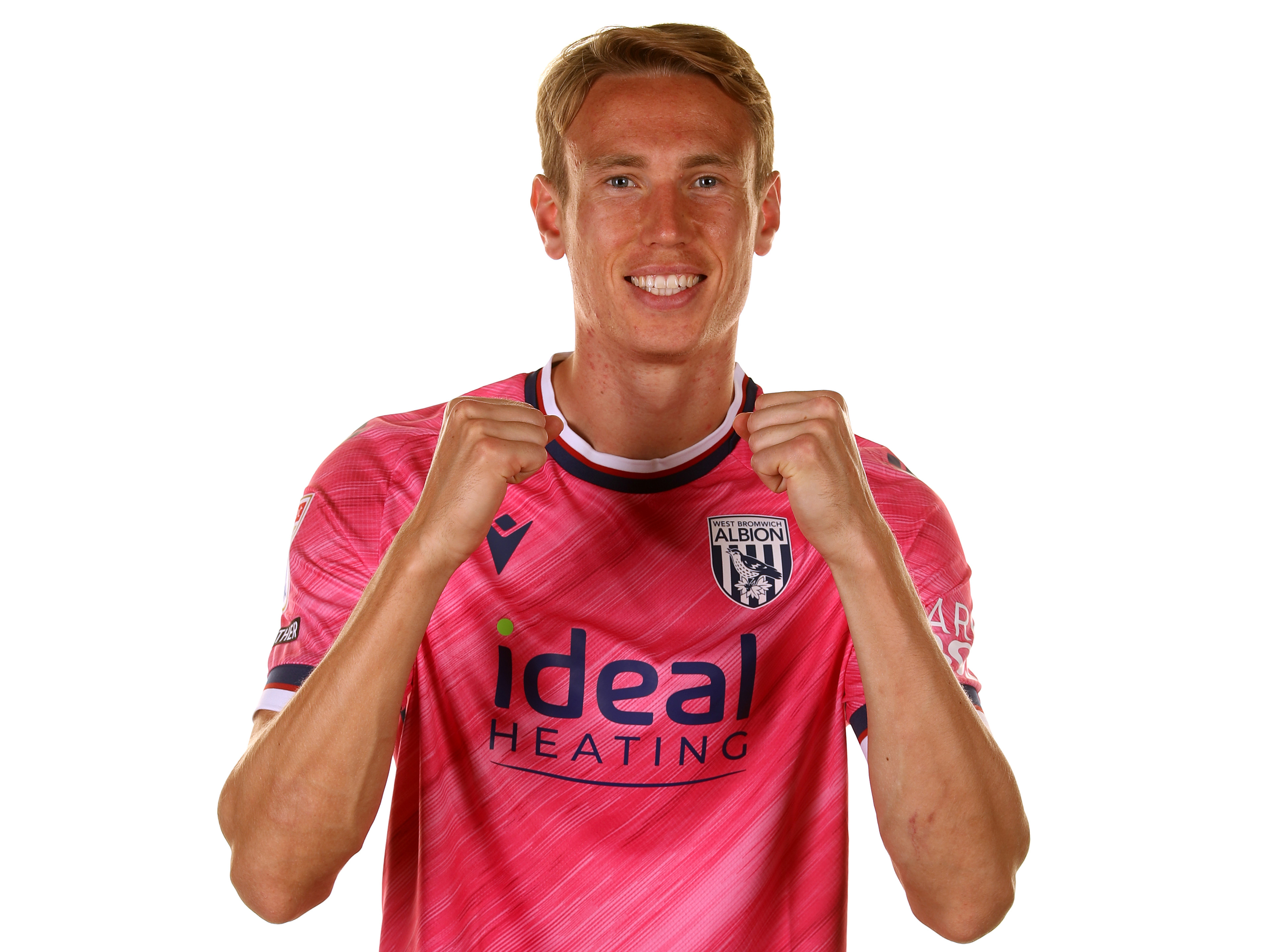 Torbjørn Heggem wearing the pink away kit with his fists clenched and smiling at the camera 