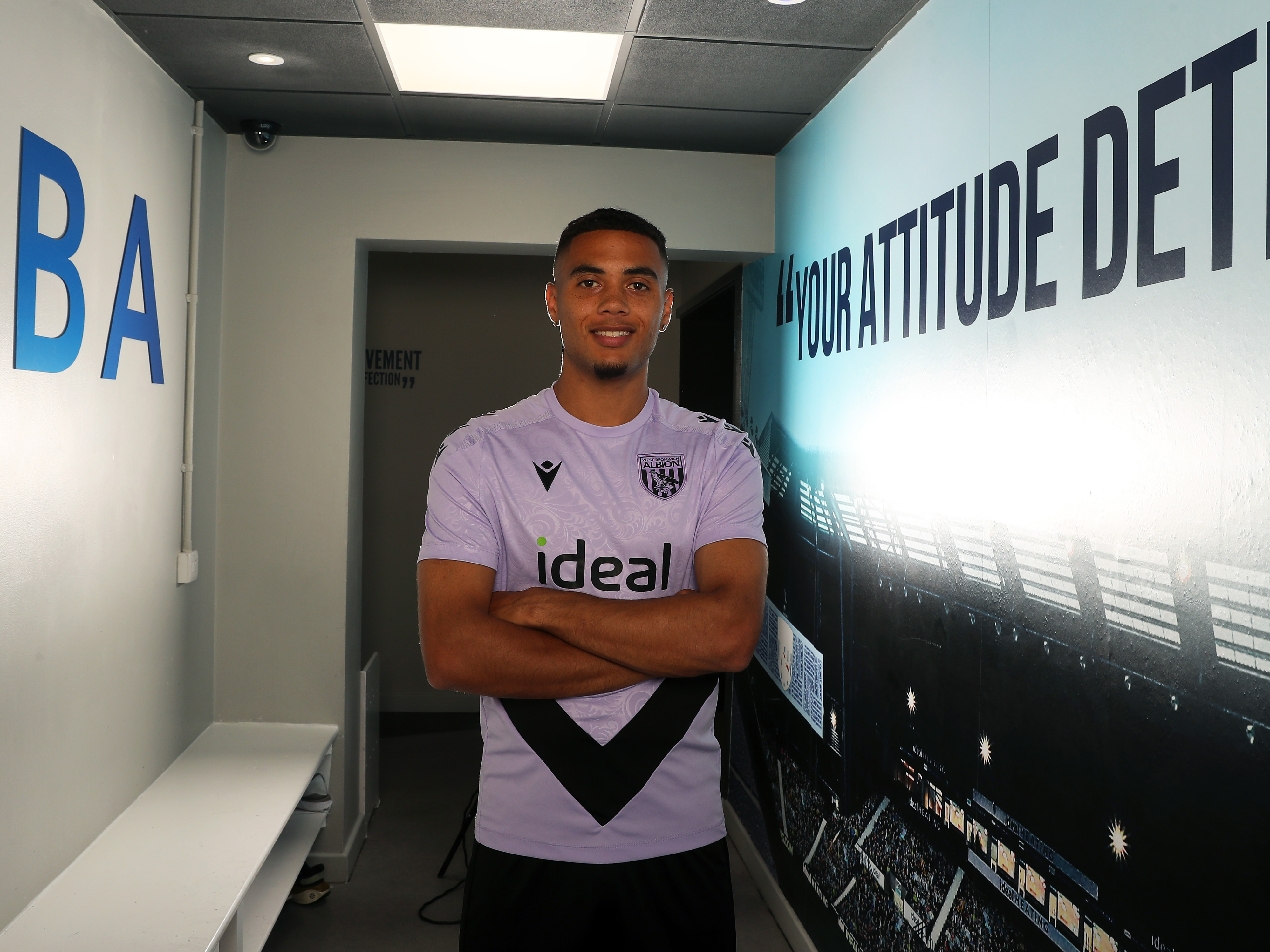 Lewis Dobbin standing in a corridor looking at the camera with his arms folded 