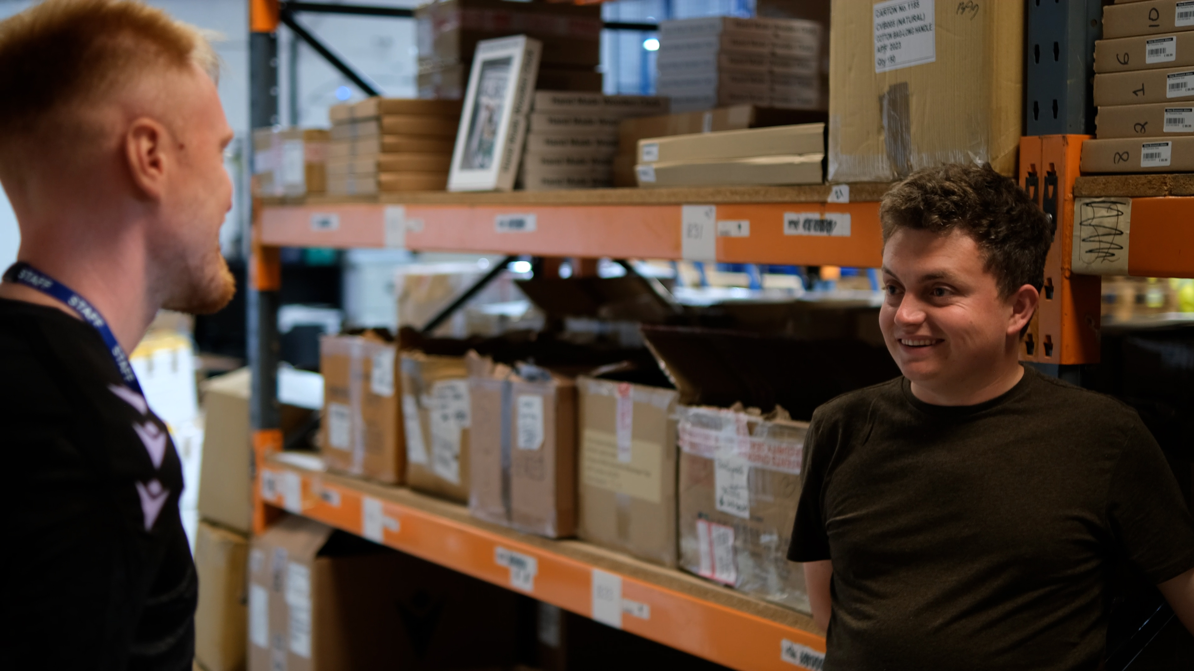 Jordy smiles, talking to the HATCH Project Coordinator during his shift at the Albion storage warehouse.