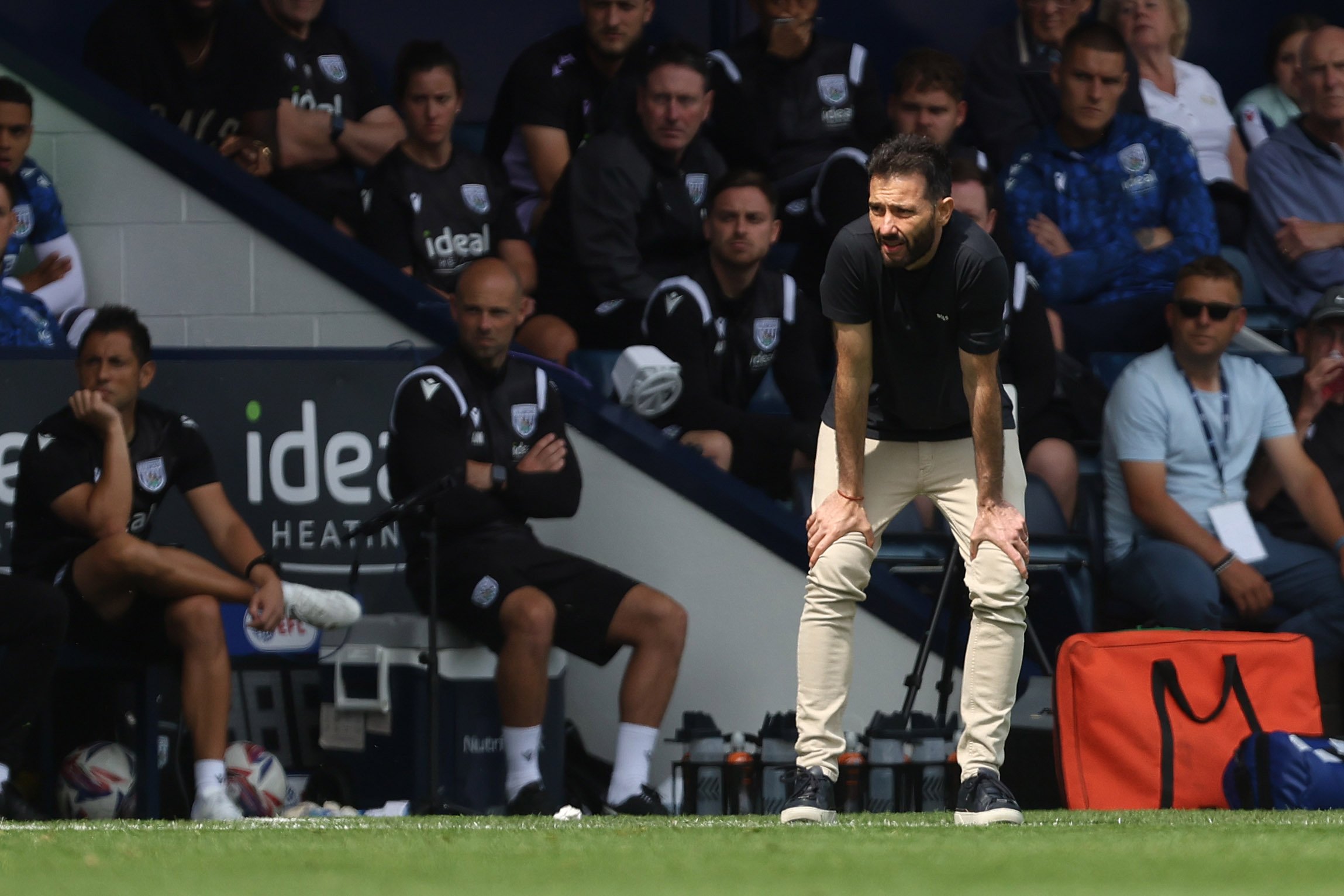 Carlos Corberán with his hands on his knees on the side of the pitch at The Hawthorns 