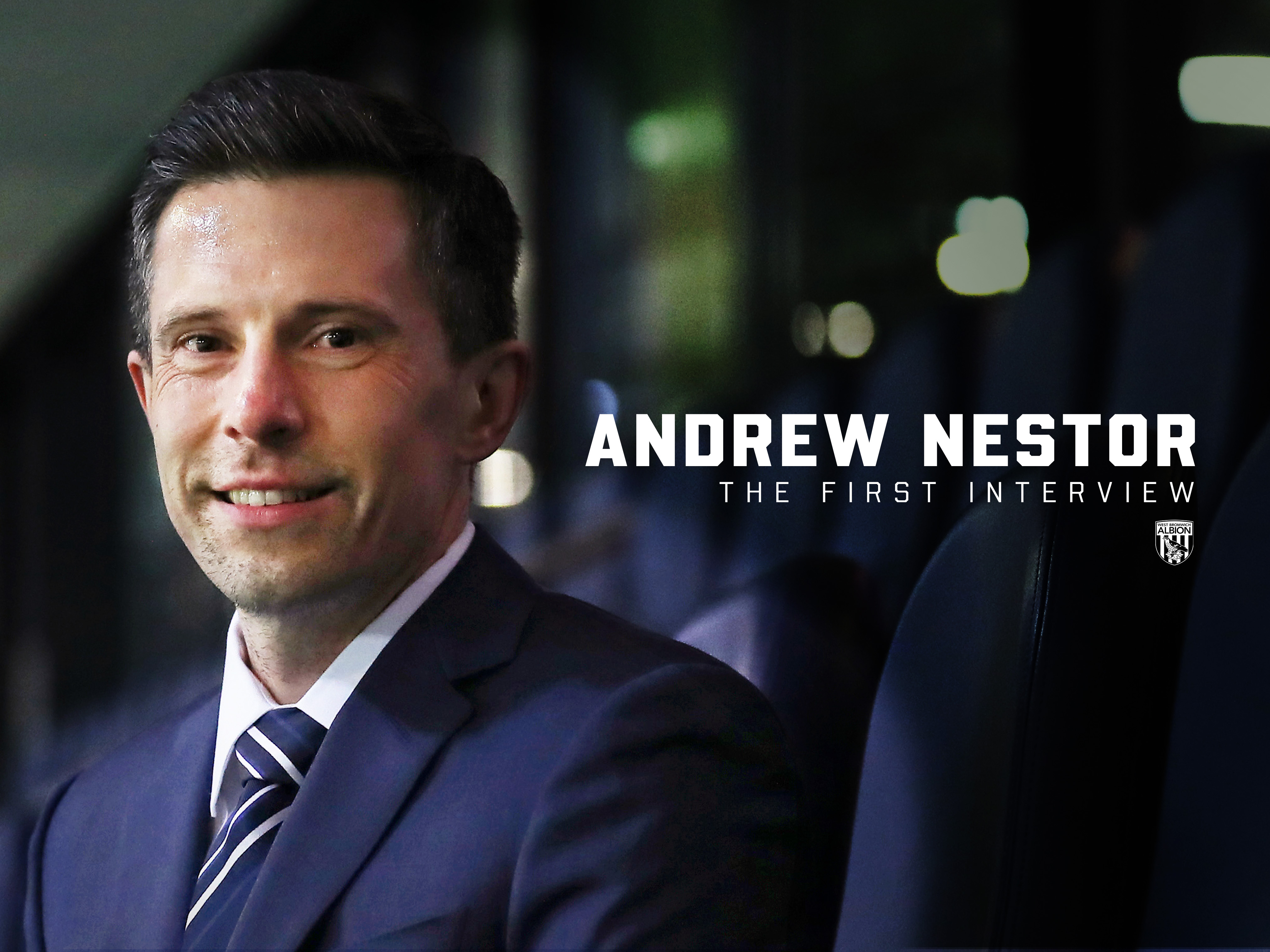 Andrew Nestor smiling at the camera while sat in a suit 