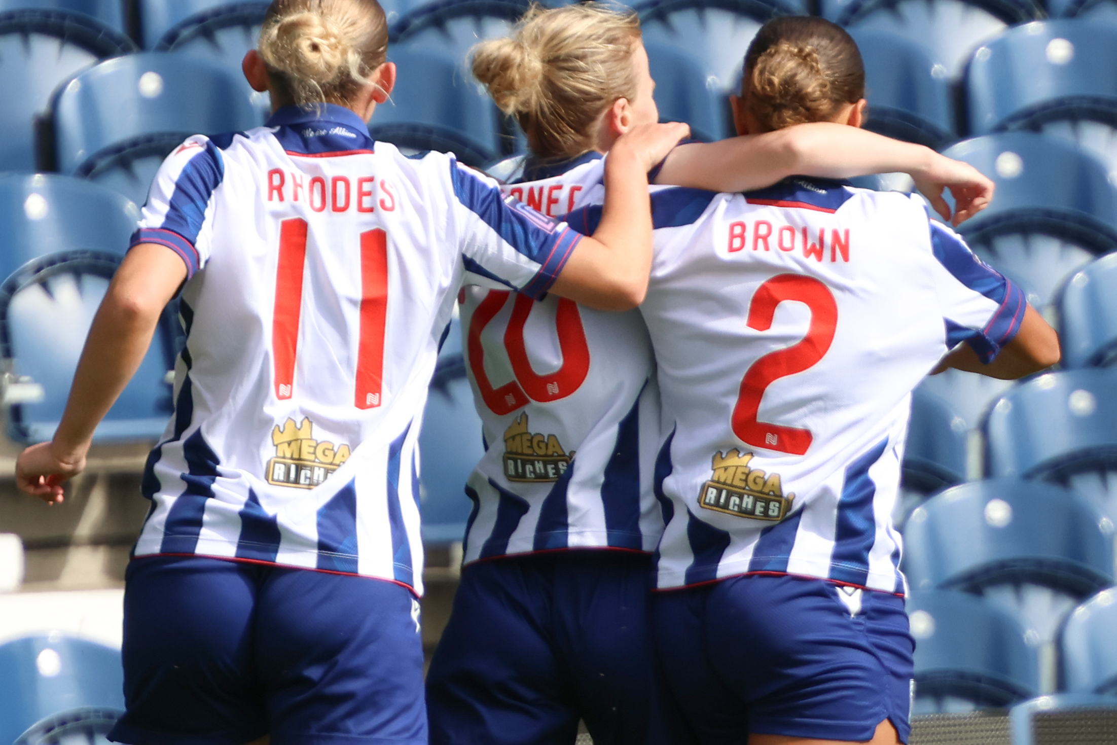 Pheobe Warner celebrates with Ash Brown and Marli Rhodes after scoring at The Hawthorns wearing the home kit 