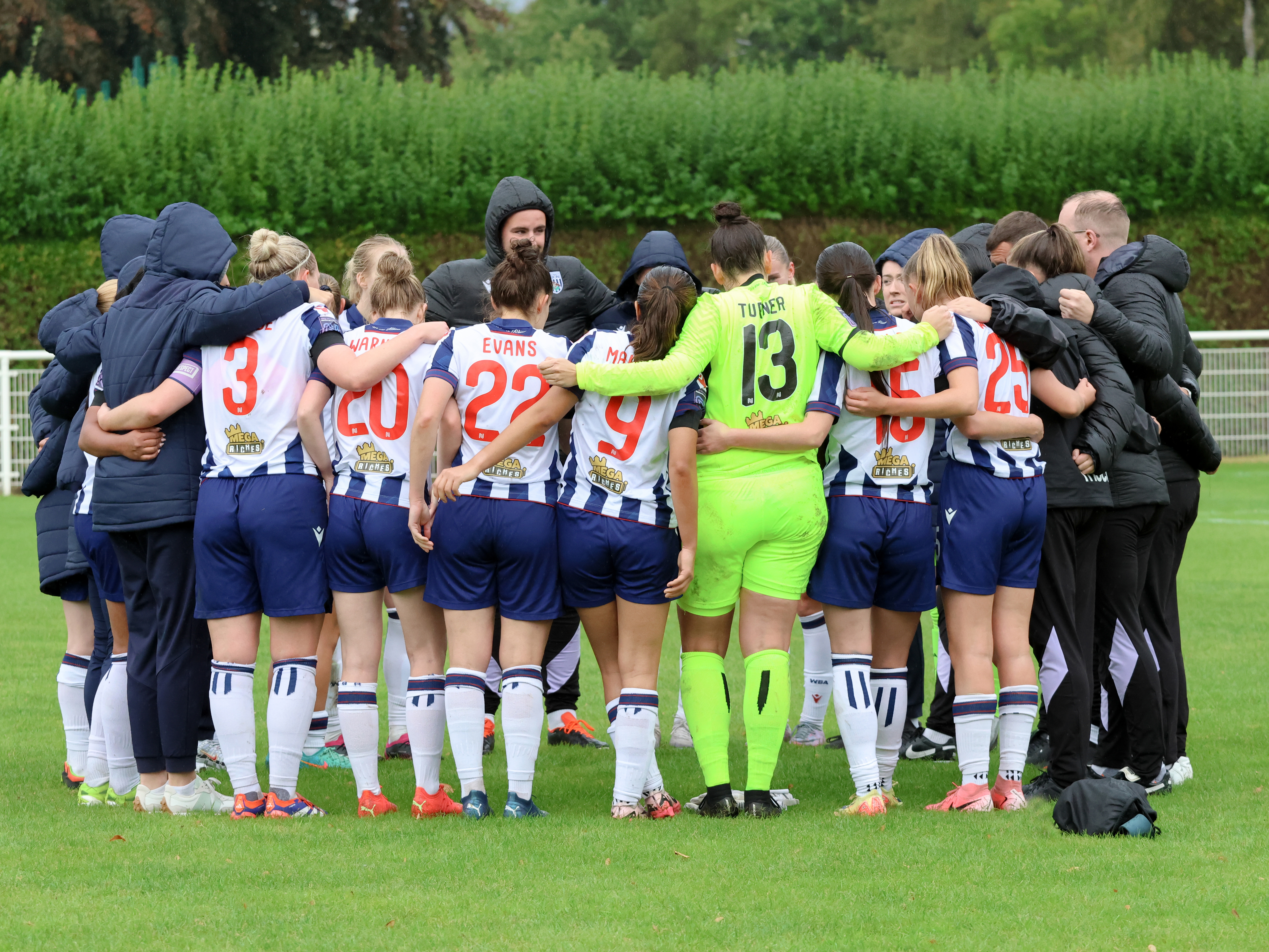 Albion Women team huddle after a game with the squad wearing home kit colours 