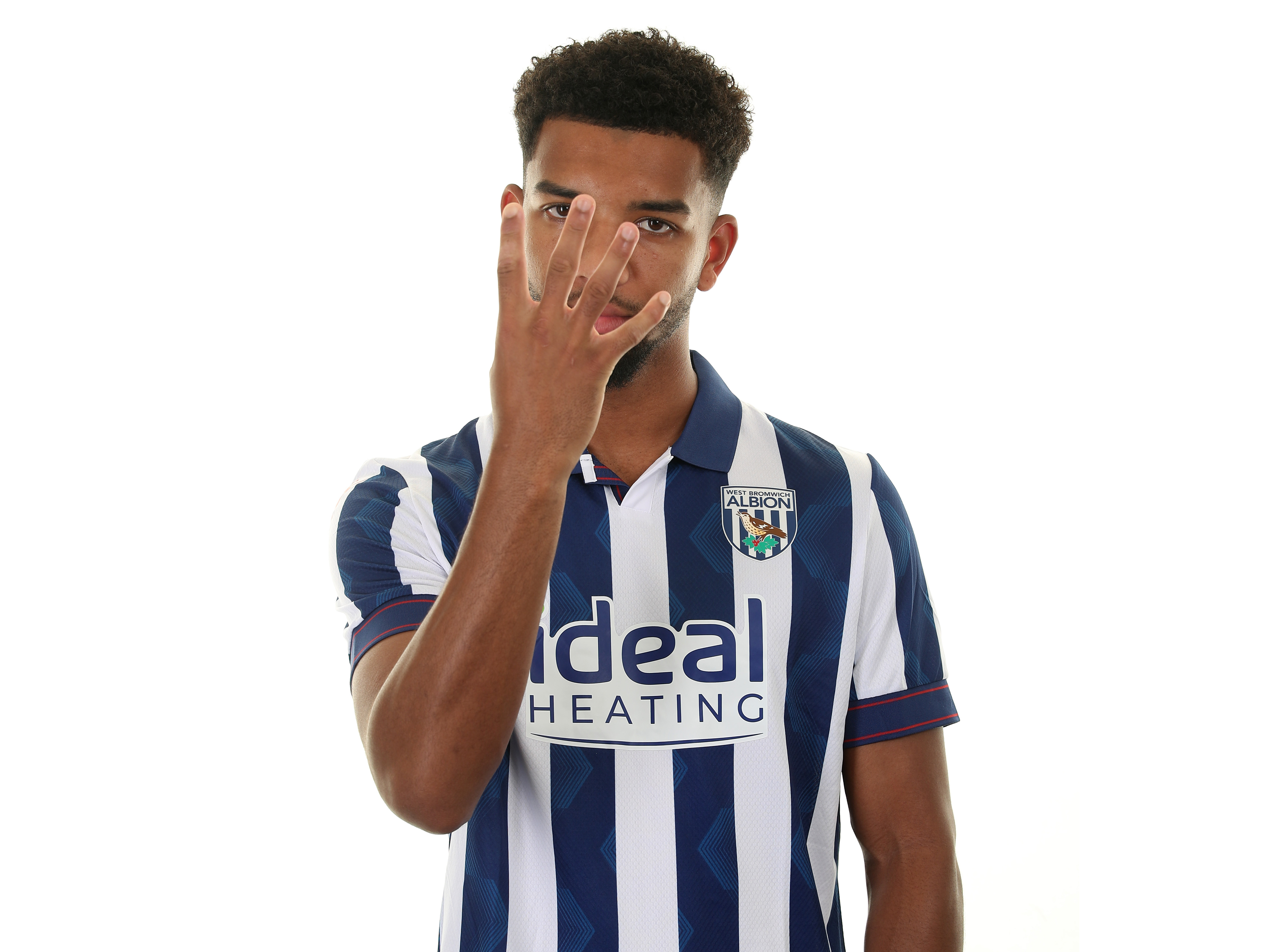 Mason Holgate holding four fingers across his face while looking at the camera in a home shirt  