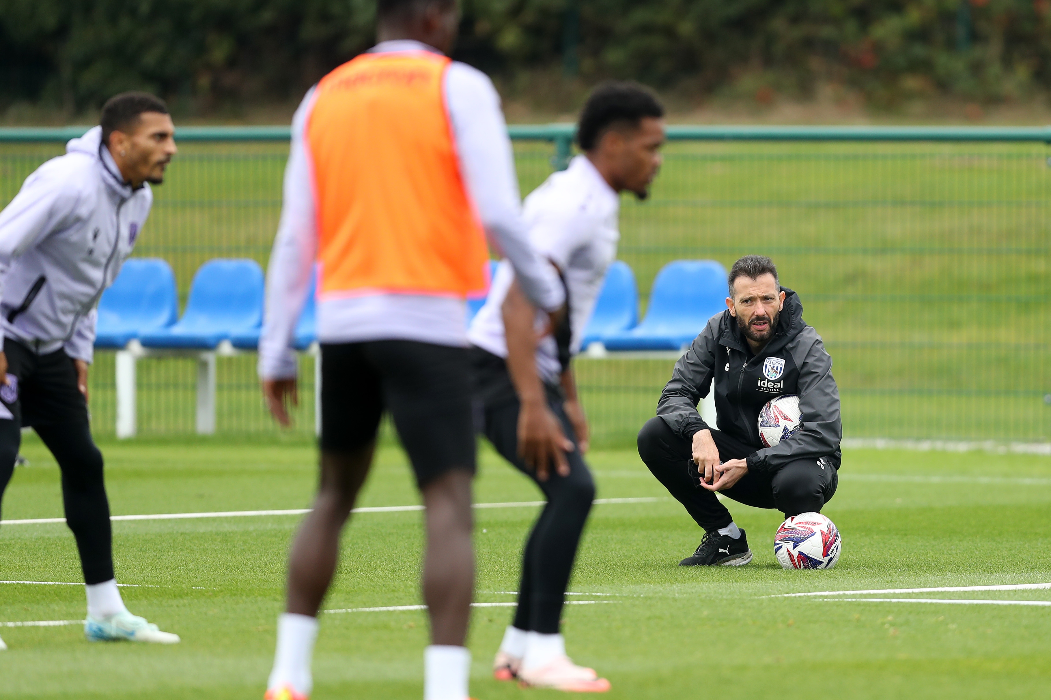 Carlos Corberán crouched down watching a training session 