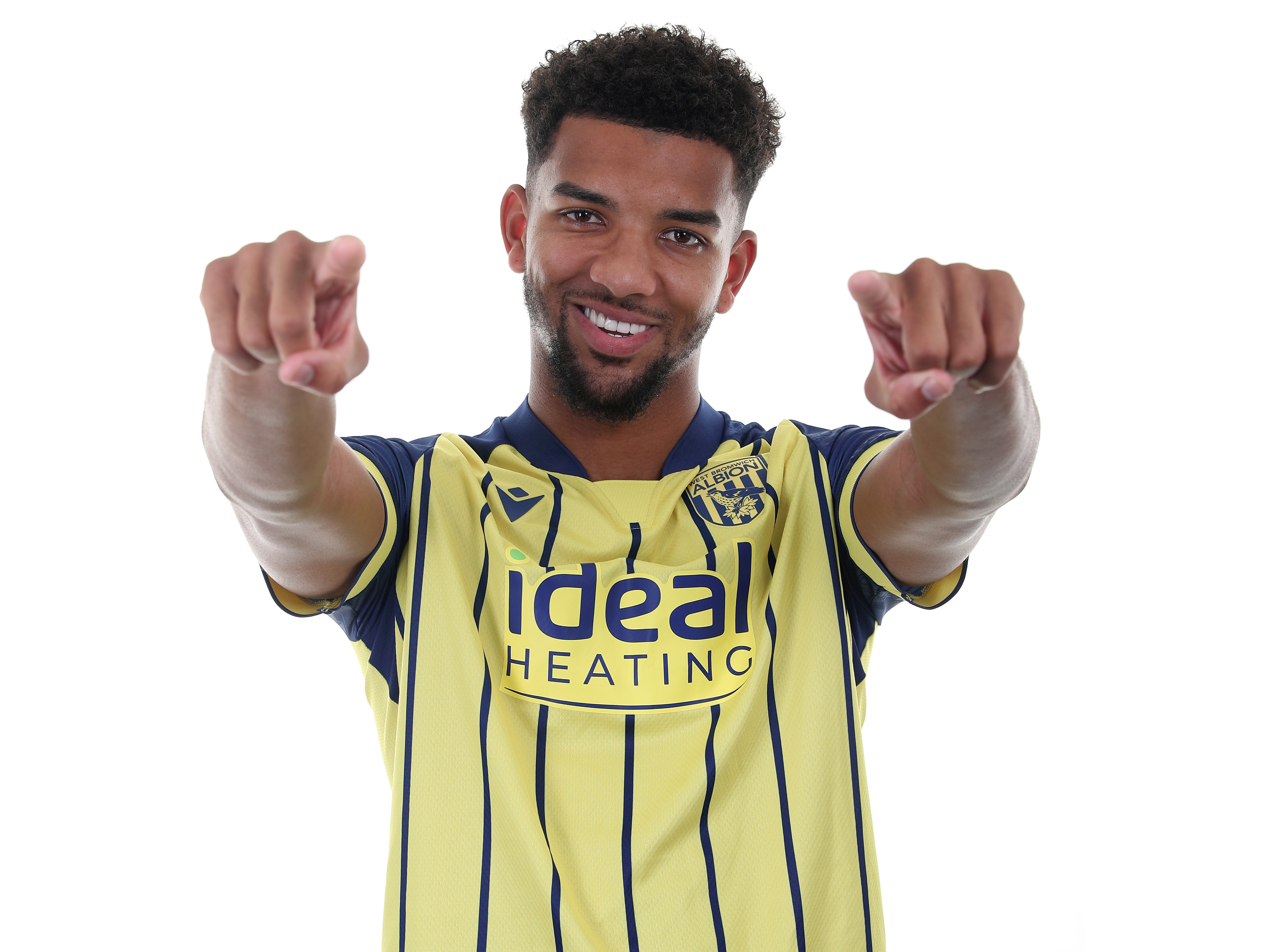 Mason Holgate smiling and pointing at the camera while wearing a yellow away kit