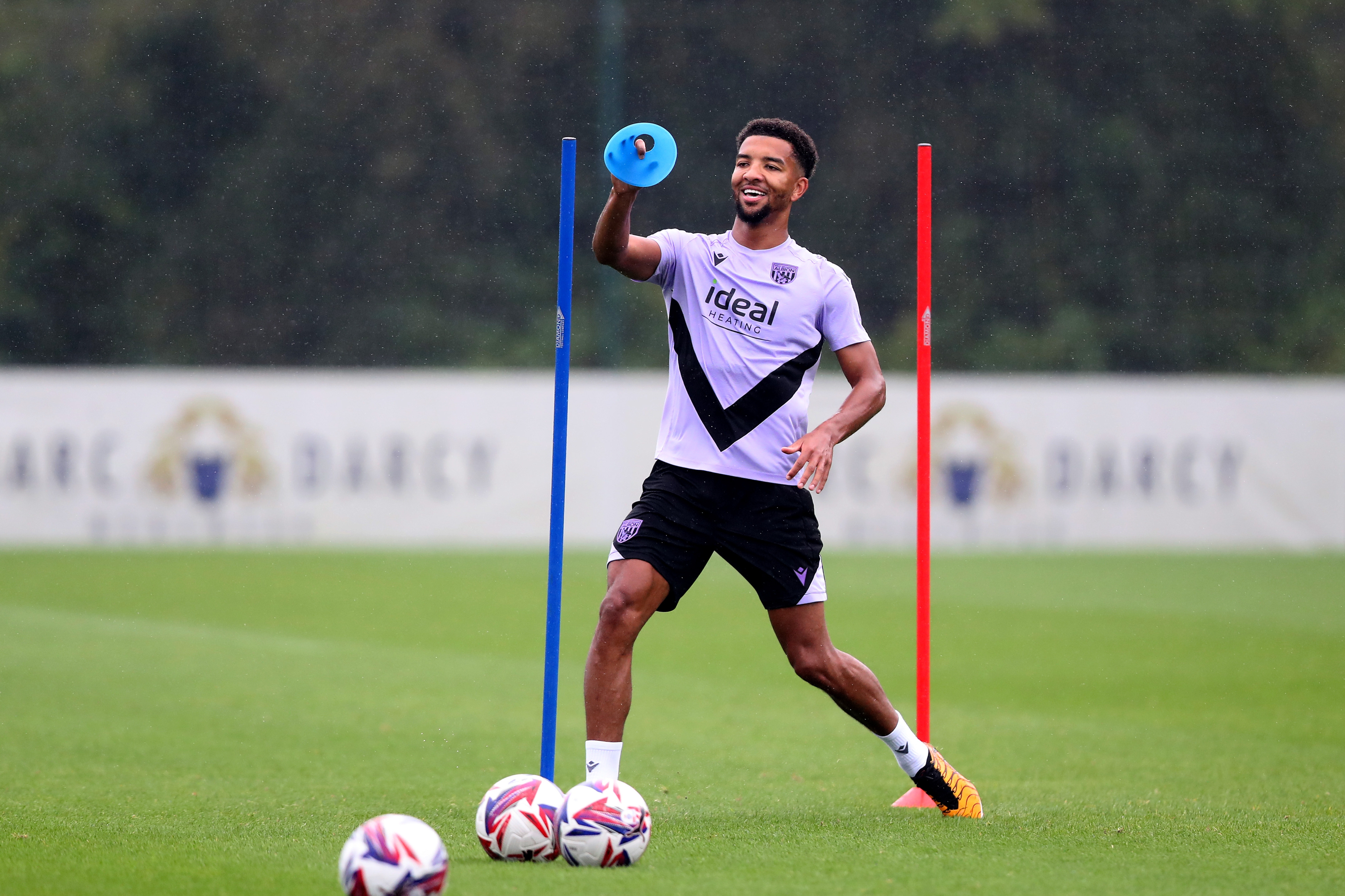 Mason Holgate smiling with a cone in his hand and three balls at his feet during a training session 