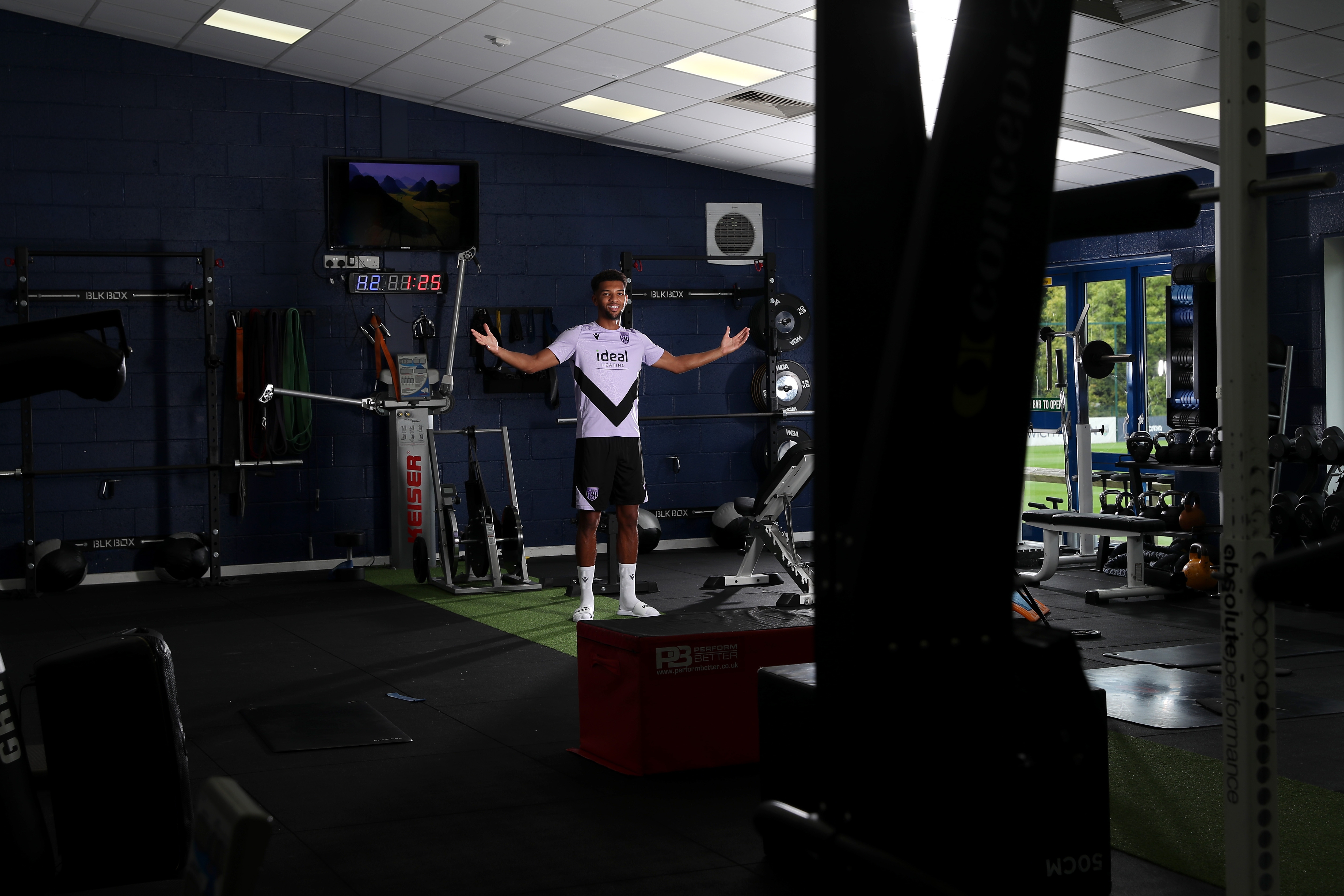 Mason Holgate smiling at the camera and holding his arms out while stood in the gym