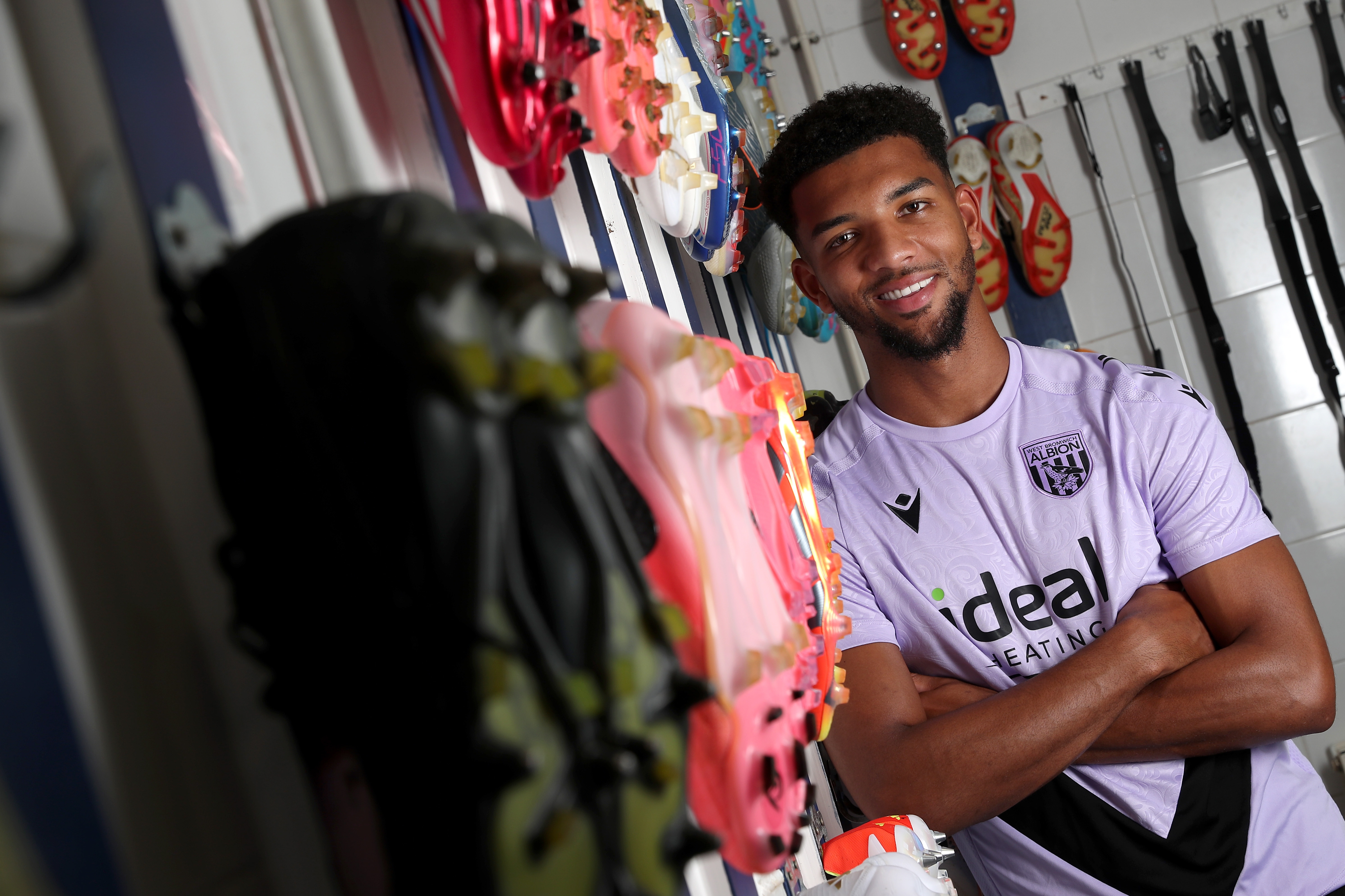 Mason Holgate smiling at the camera with his arms folded while stood in the boot room