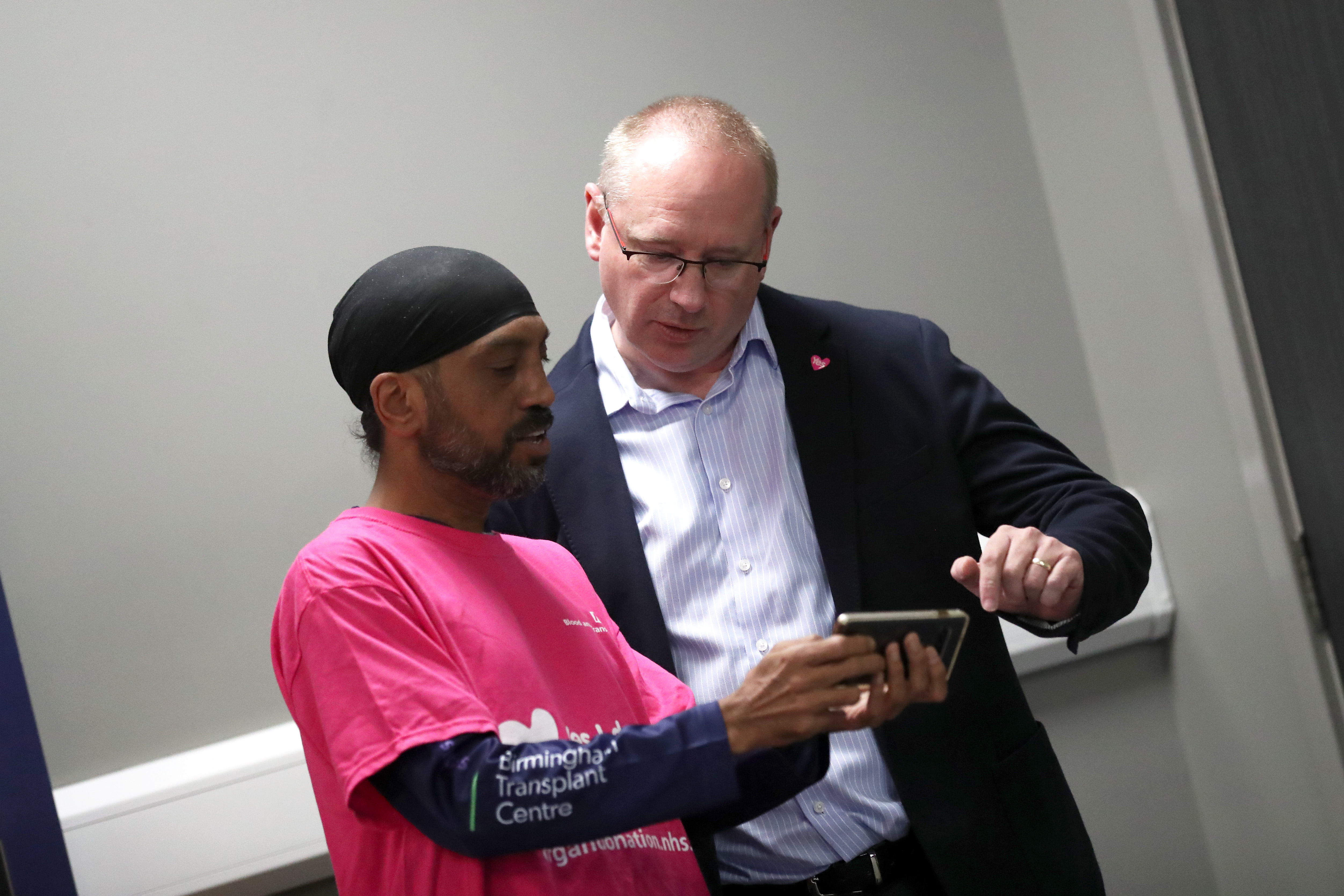 Albion Managing Director Mark Miles looks at a phone with a member of the Birmingham Adult Transplant Sport Team