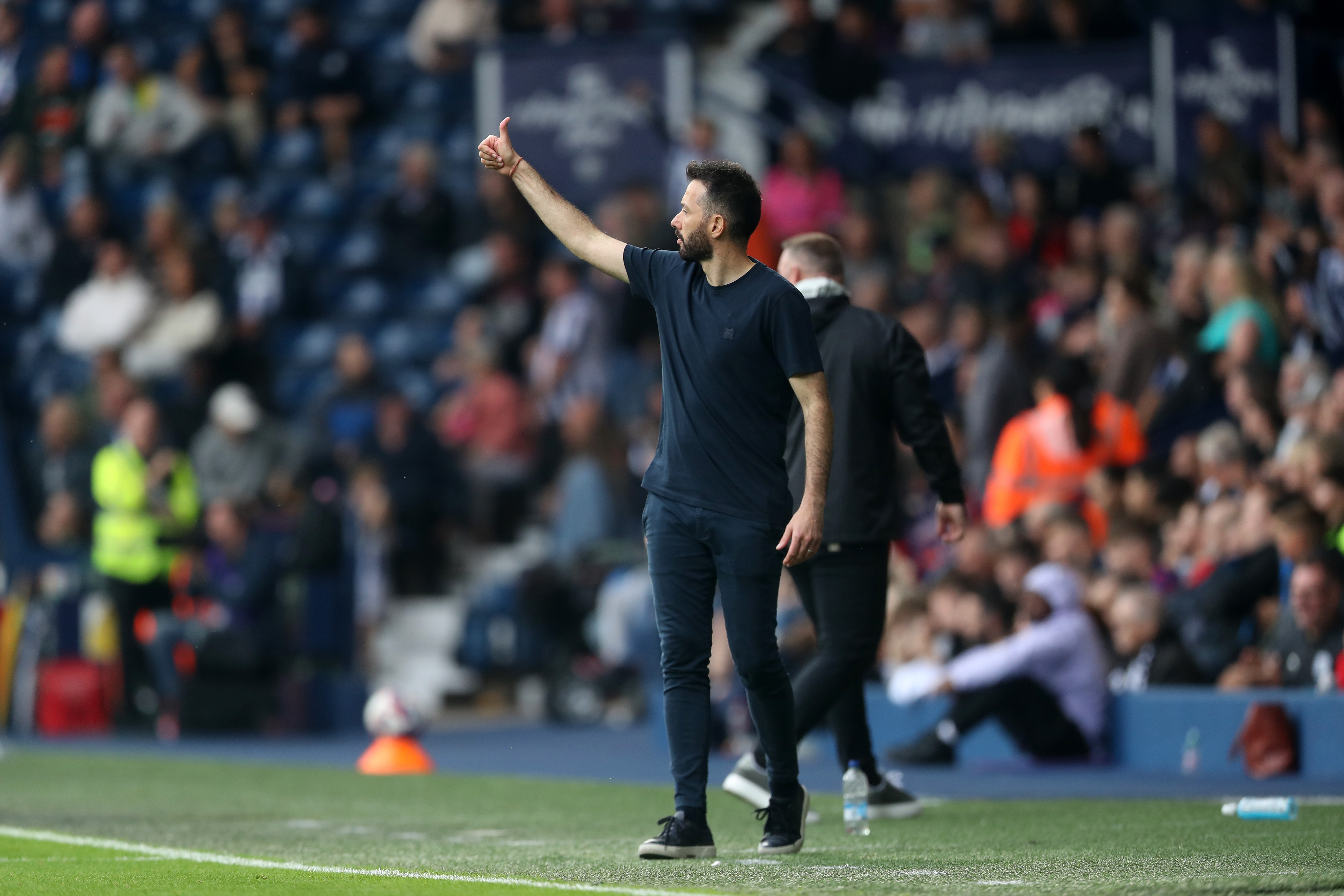 Carlos Corberán with his thumb up on the side of the pitch at The Hawthorns 