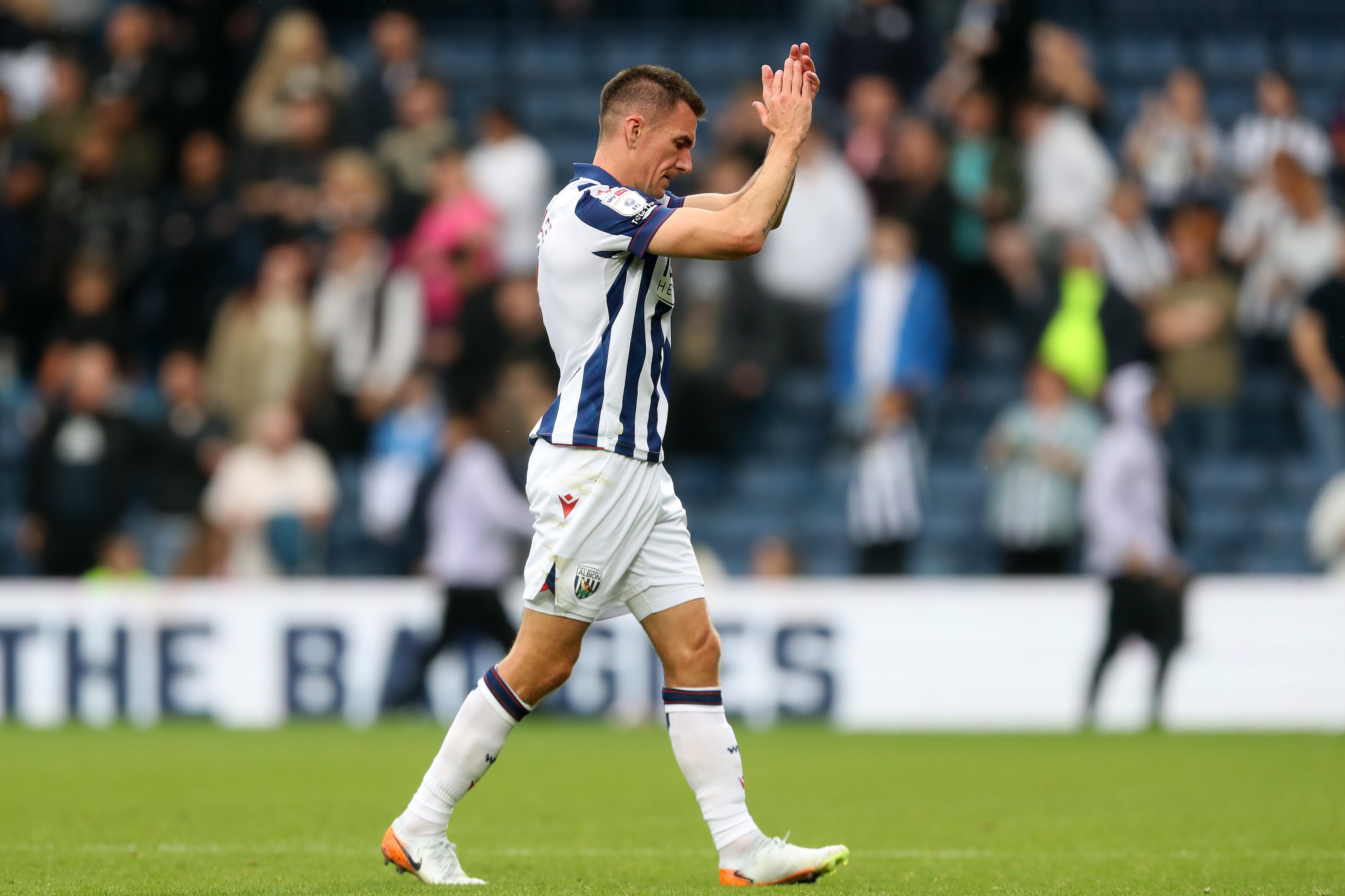 Jed Wallace applauds Albion fans at The Hawthorns while wearing the home kit 