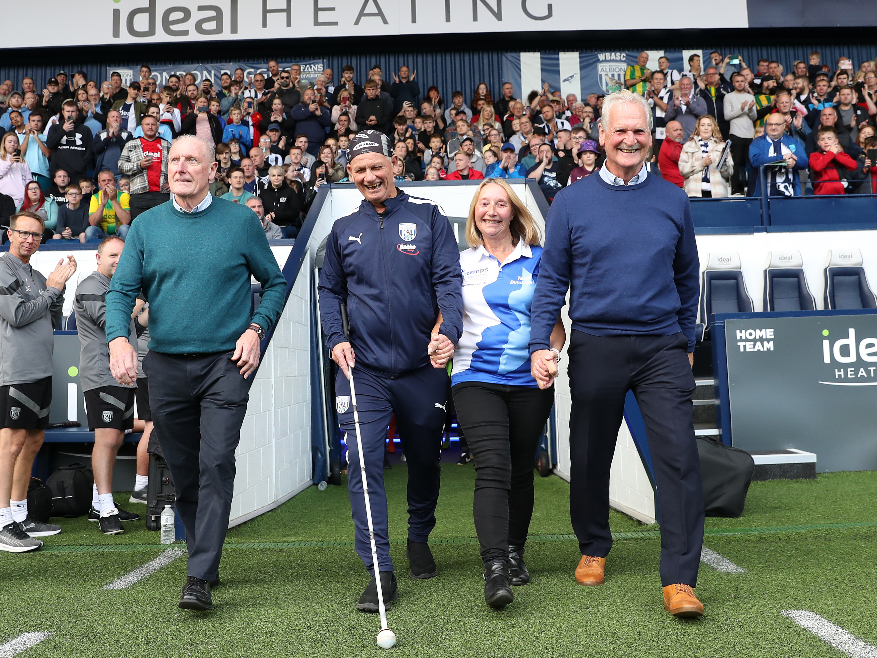 Blind Dave Heeley walking out of the tunnel at The Hawthorns with Tony Brown, his wife and Ally Robertson 