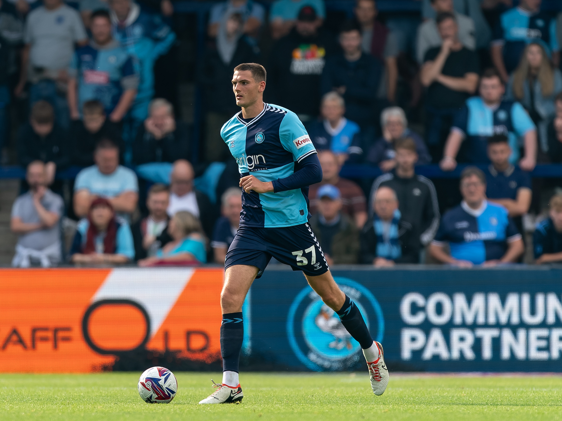 Caleb Taylor, in the navy and sky blue home kit of loan club Wycombe Wanderers, carrying the ball during a League One game