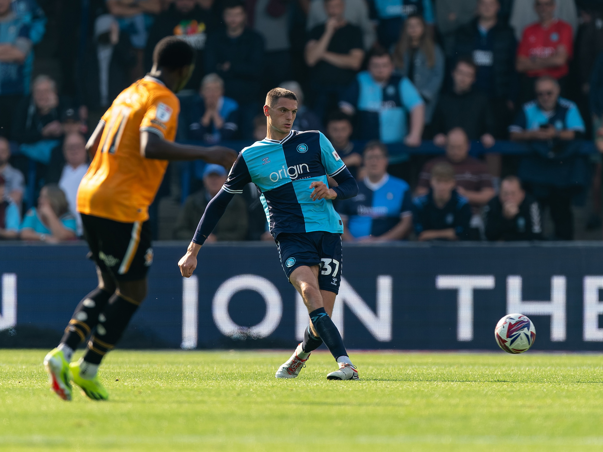 A photo of Caleb Taylor in the navy and sky blue home kit of loan club Wycombe, on the ball in League One action