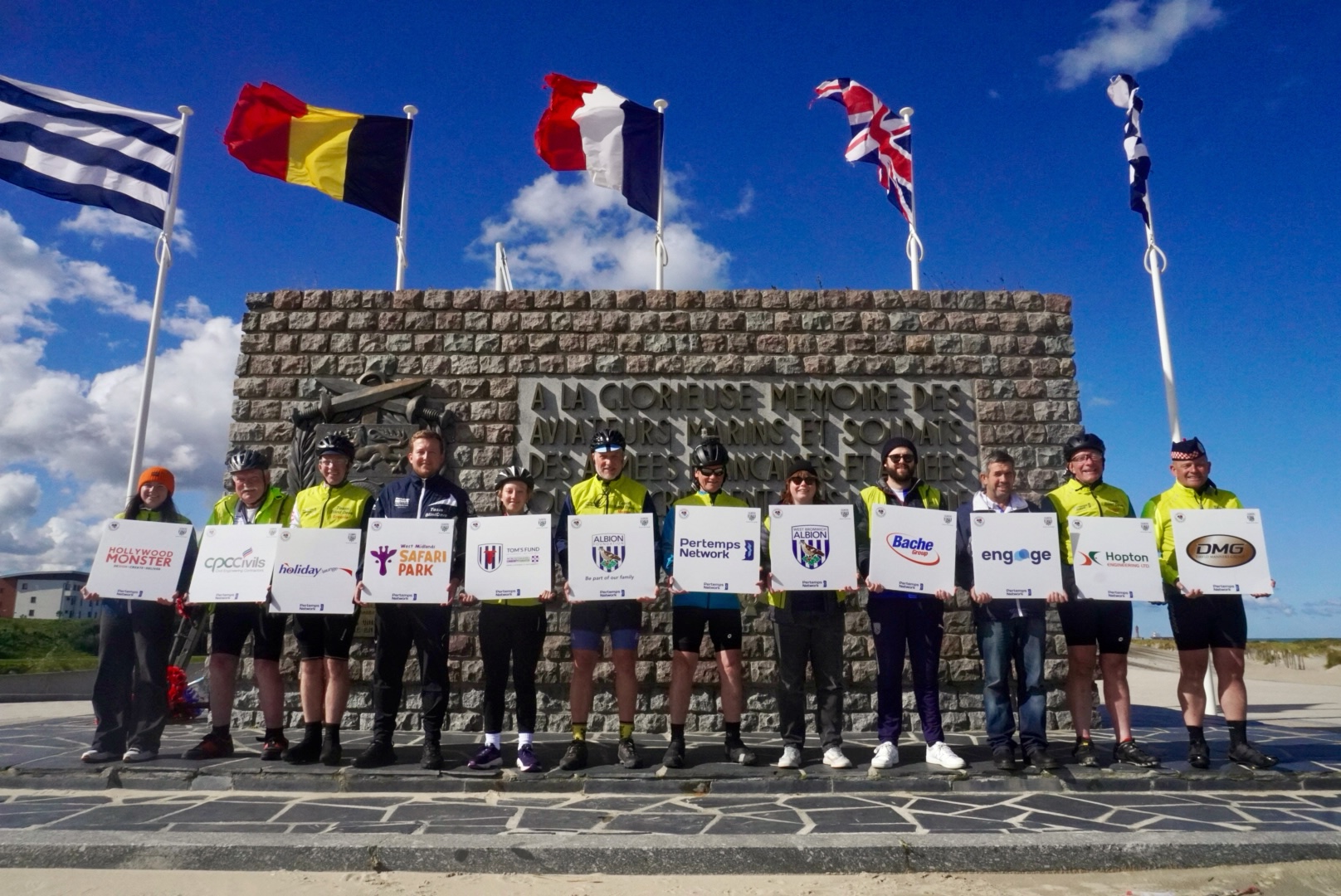 Team Blind Dave stand in front of the Dunkirk Memorial, bearing the names of sponsors for the challenge.