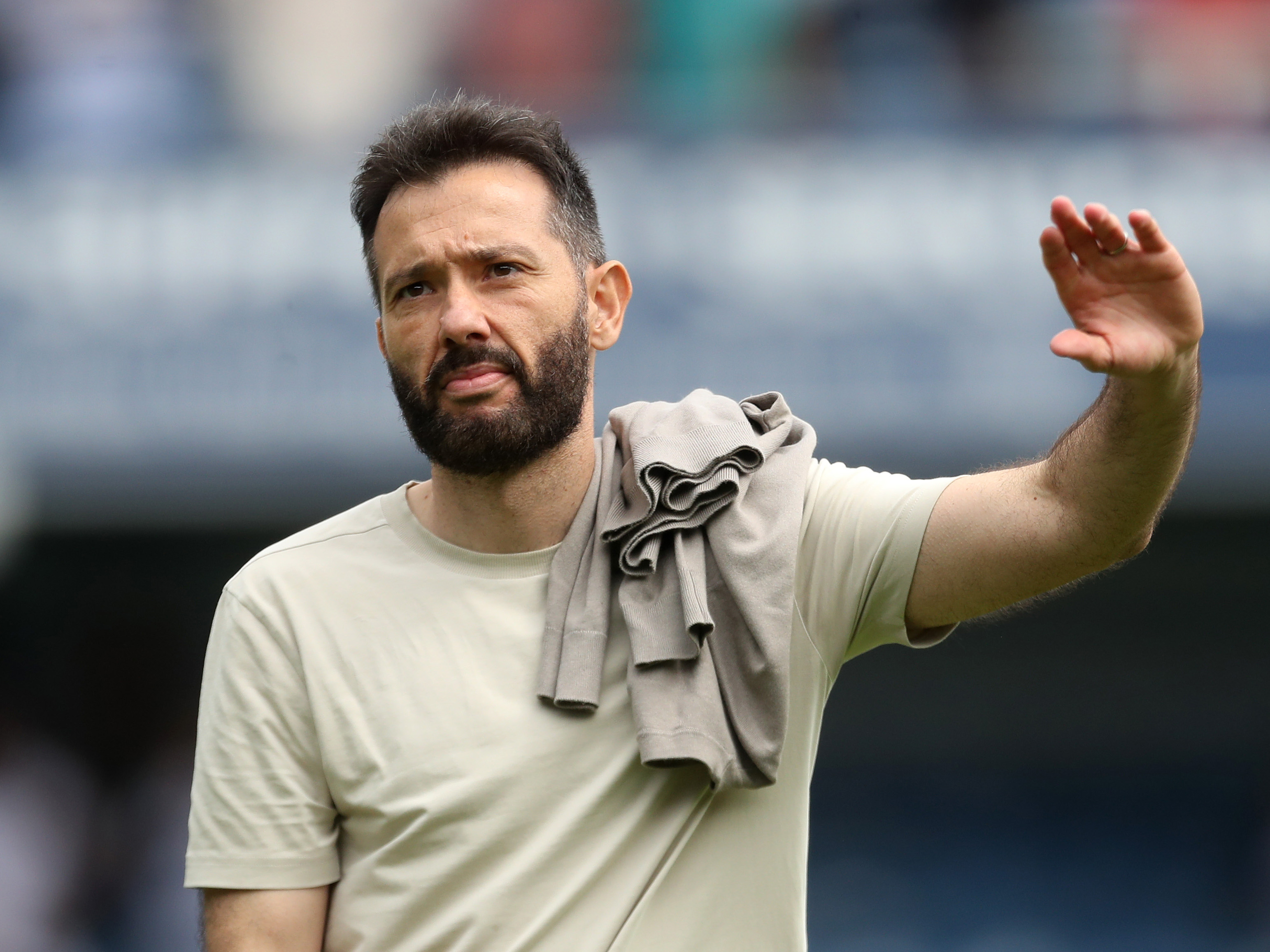 Carlos Corberán waving to Albion fans while wearing a bright t-shirt 