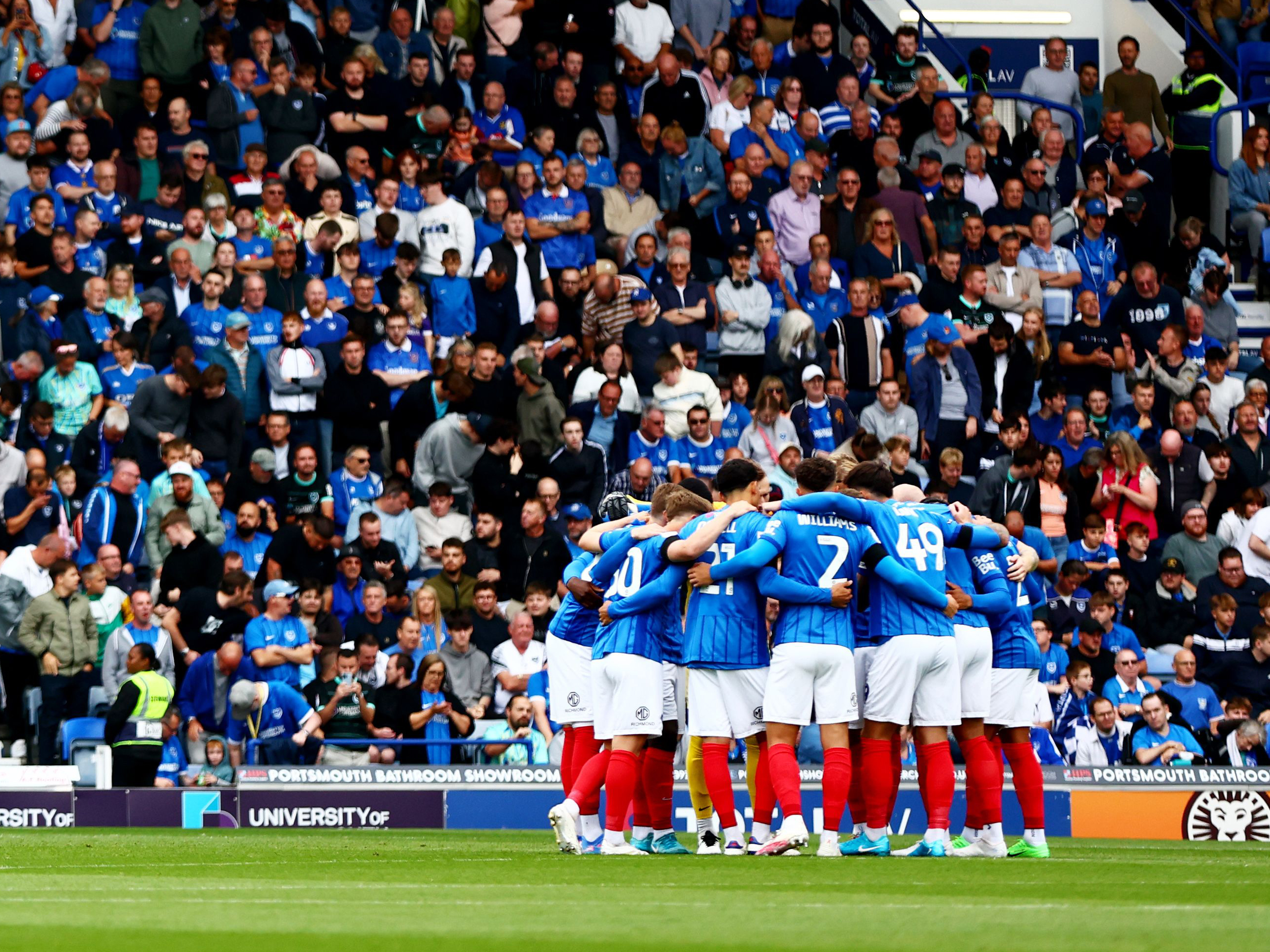 Portsmouth players in a pre-match huddle in front of their supporters 