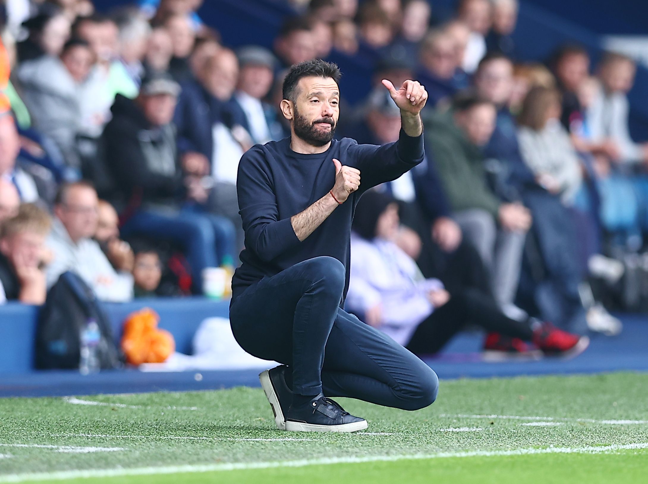 Carlos Corberán crouched down on the side of the pitch against Plymouth 