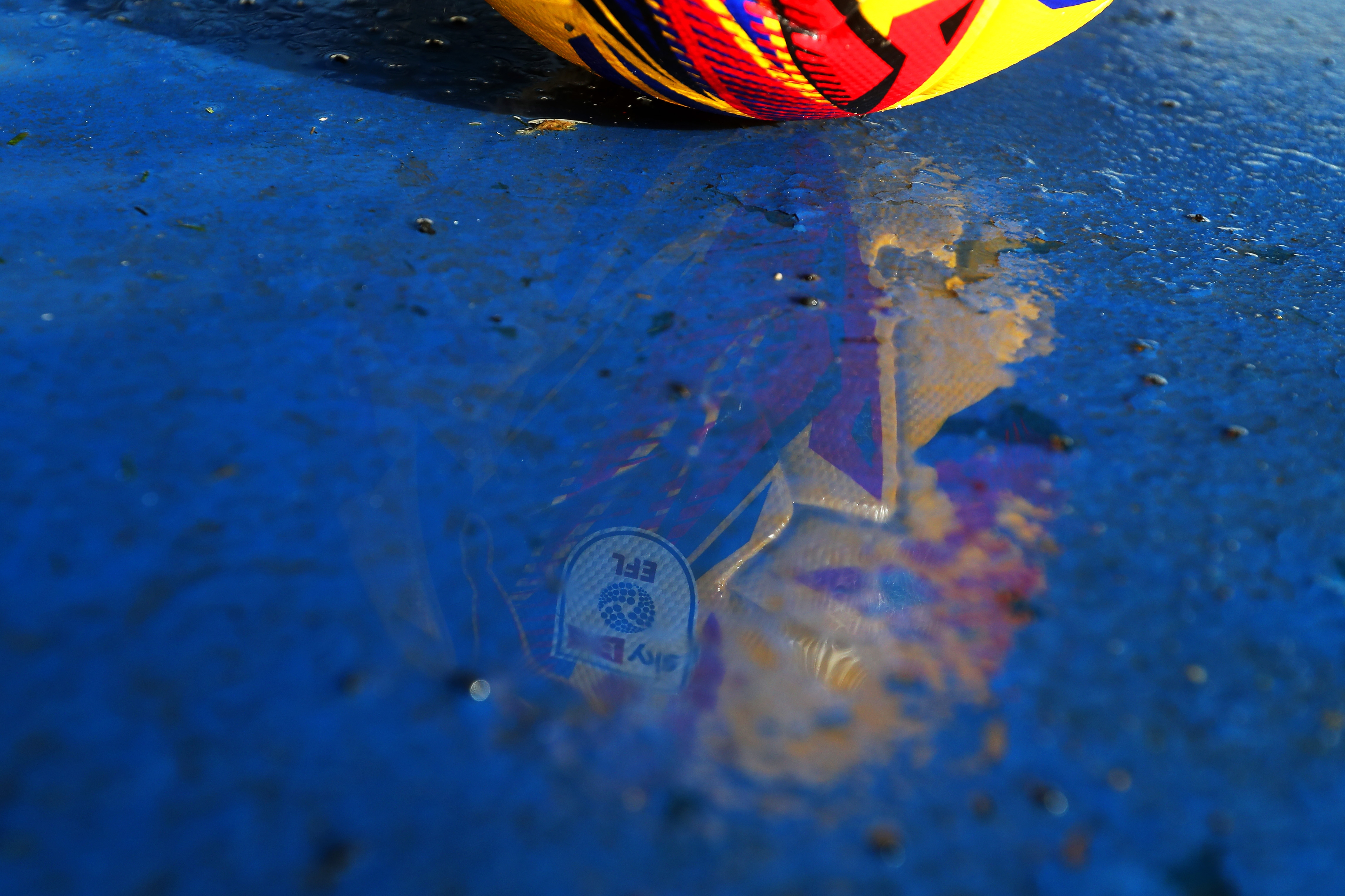 The reflection of a yellow EFL football in a puddle on the side of the pitch at The Hawthorns 