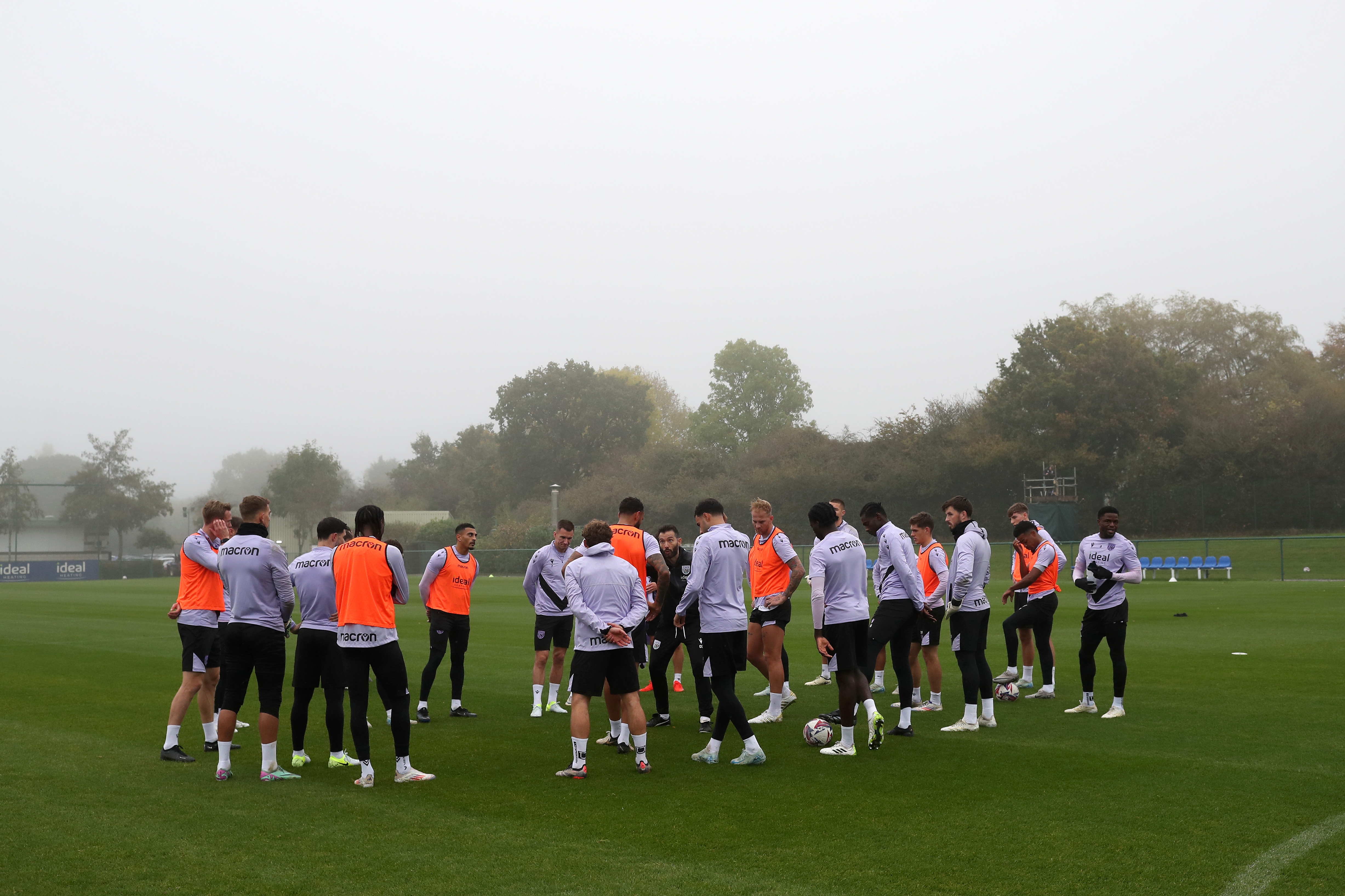 Albion's squad in a huddle on the training pitch listening to Carlos Corberán