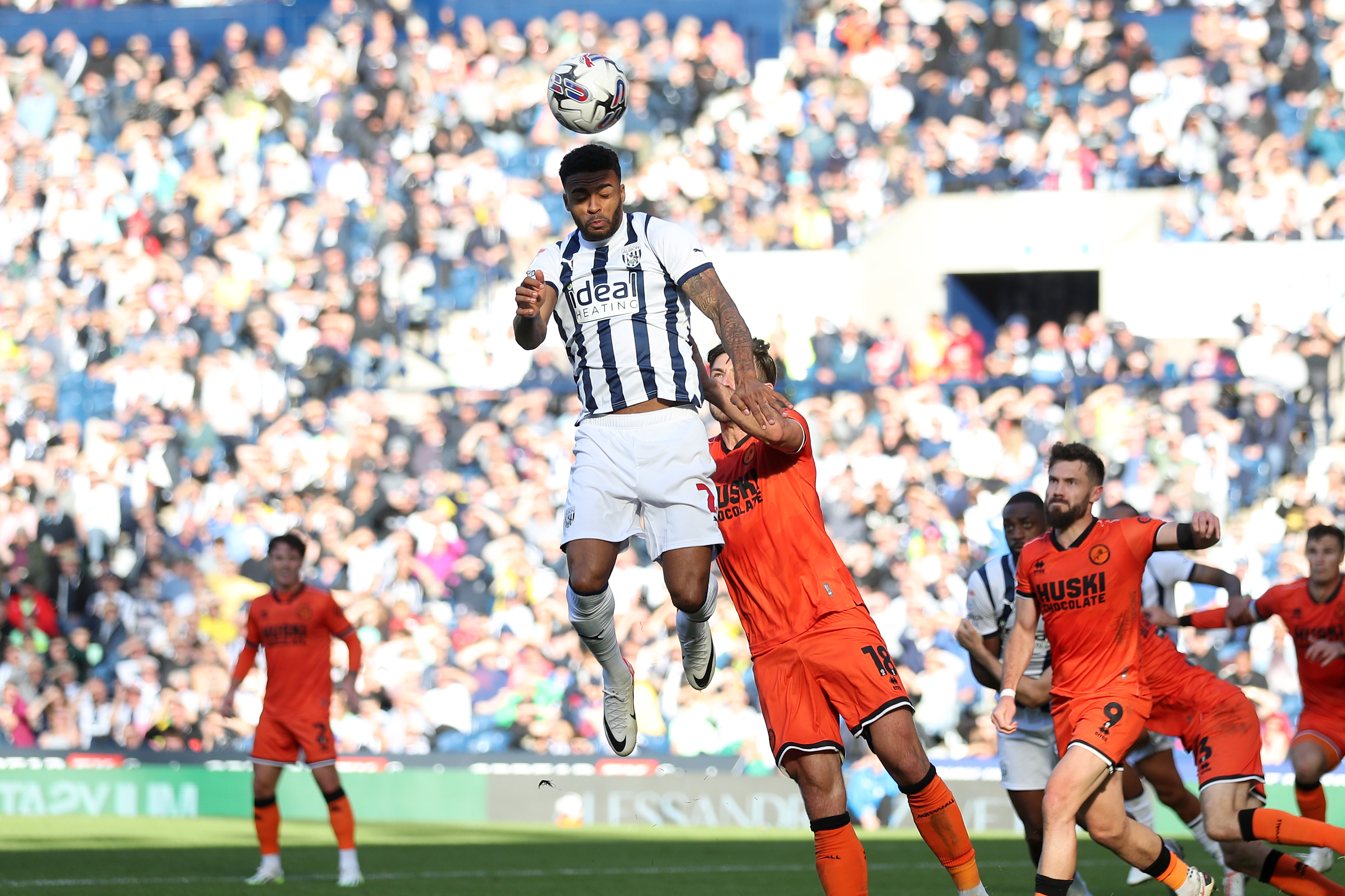 Darnell Furlong jumps for the ball against Millwall at The Hawthorns wearing the home shirt in September 2023 