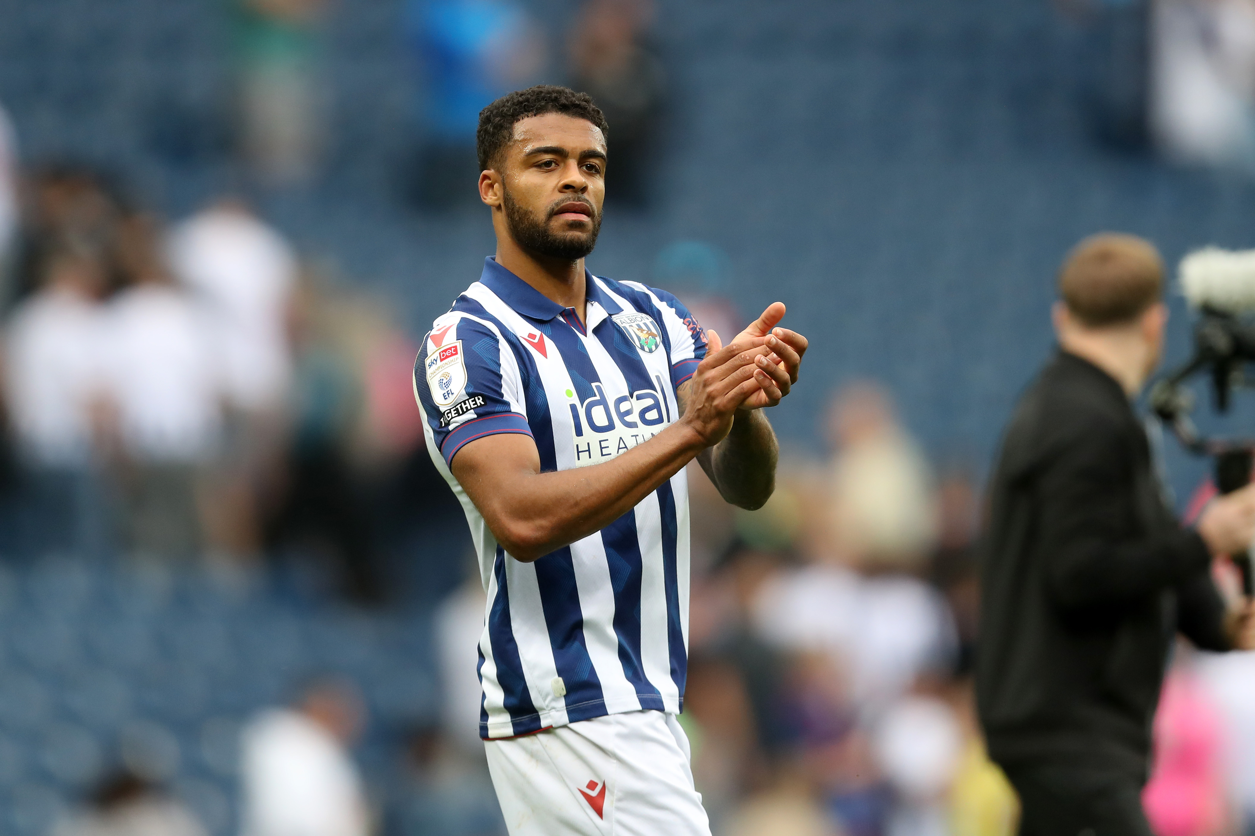 Darnell Furlong applauding Albion fans while wearing the home kit