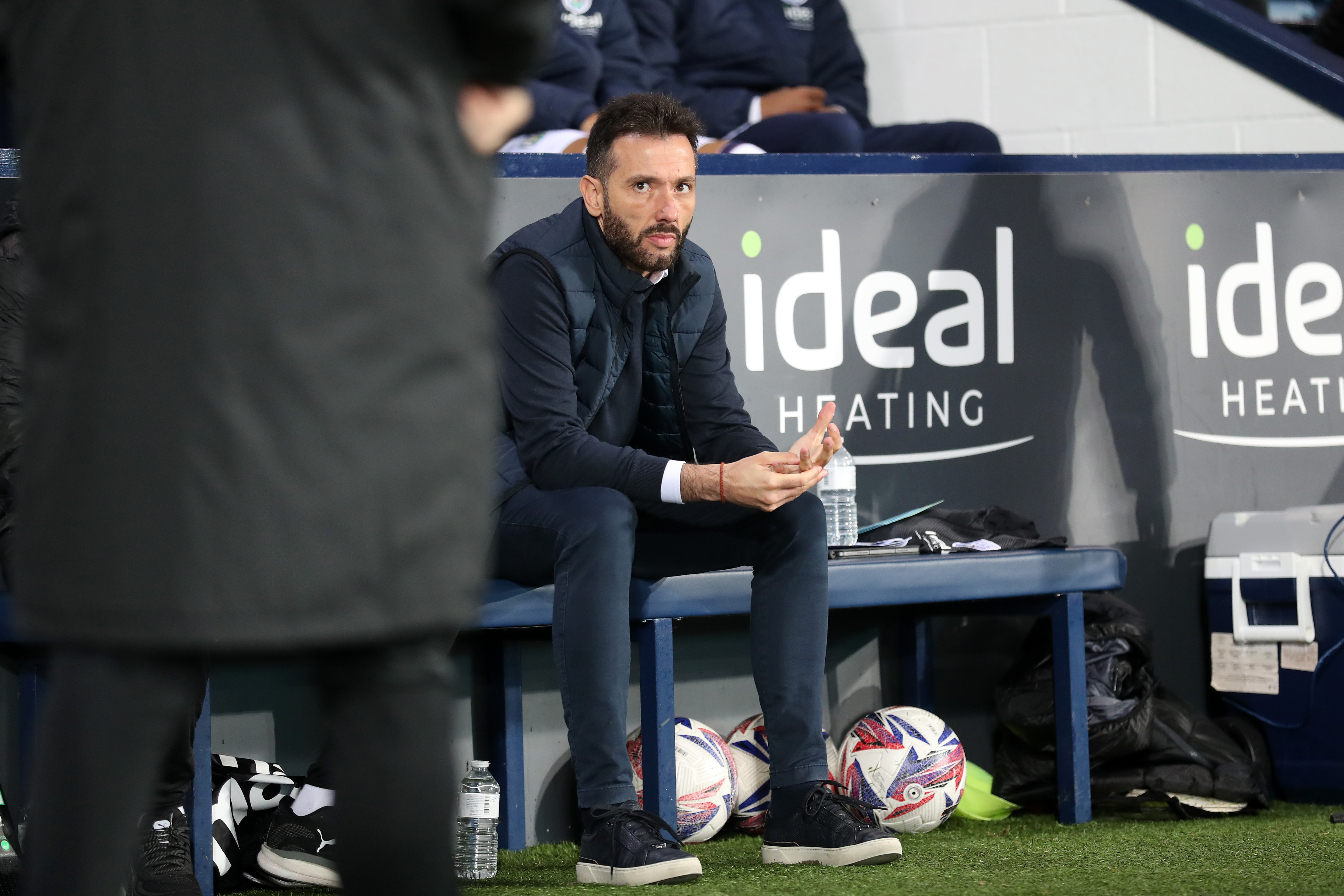 Carlos Corberán sat on a bench at the side of the pitch at The Hawthorns 