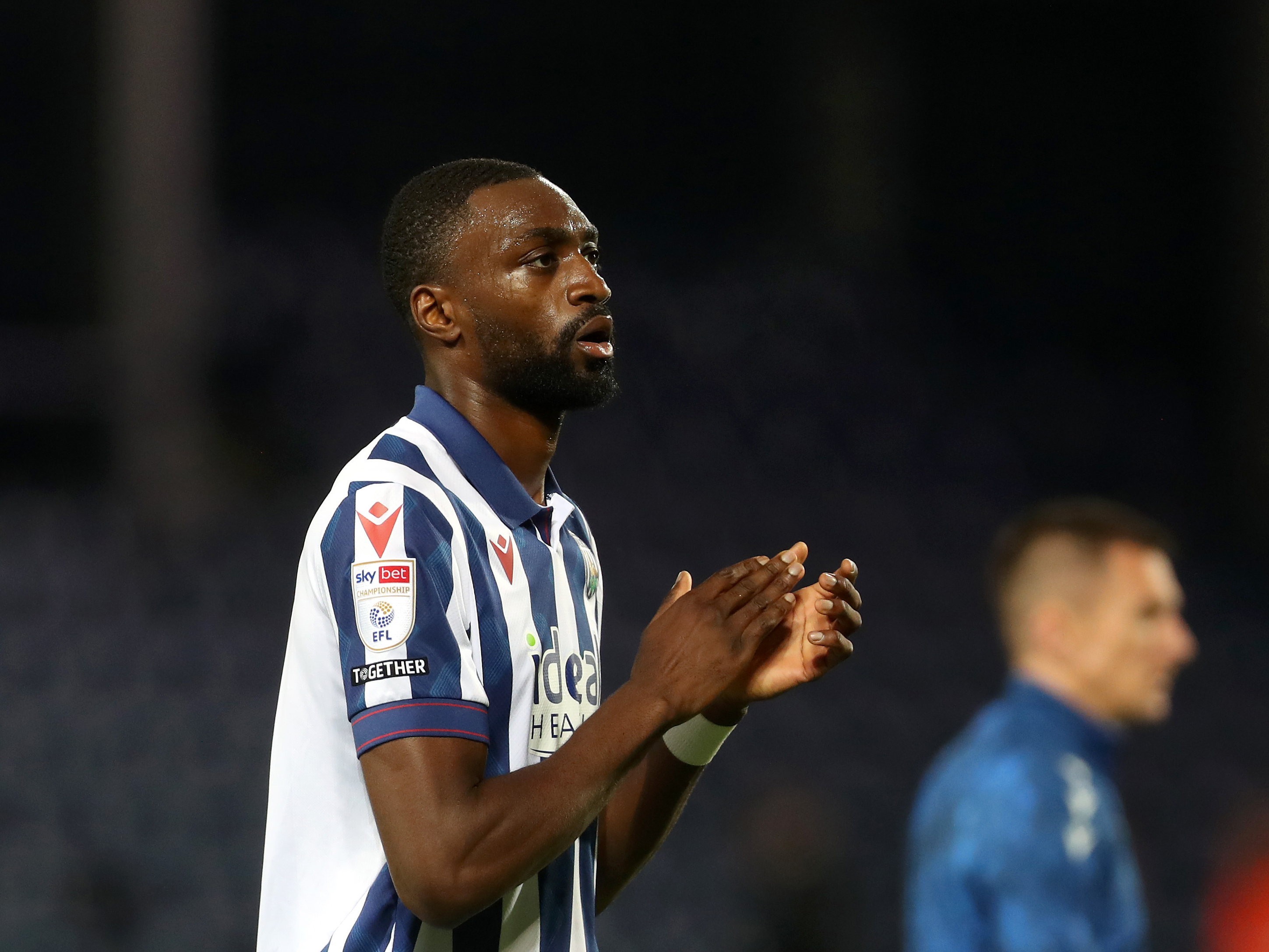 Semi Ajayi applauding Albion fans while wearing the home kit