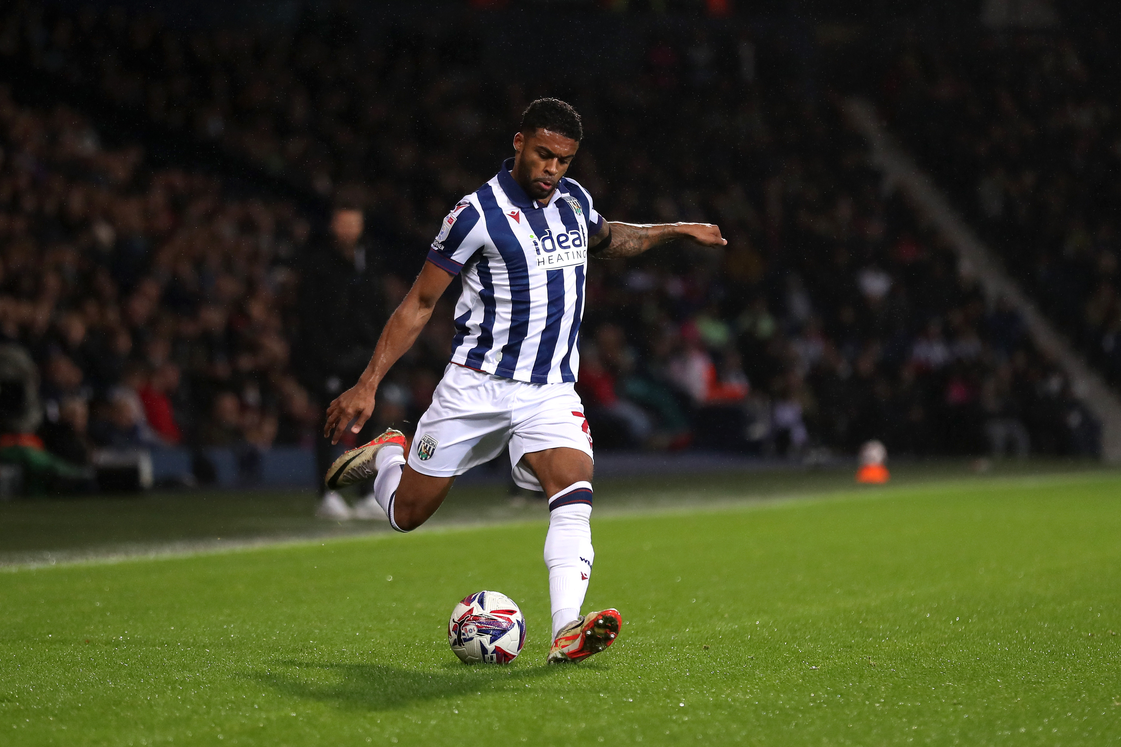 Darnell Furlong crossing the ball at The Hawthorns wearing a home kit 