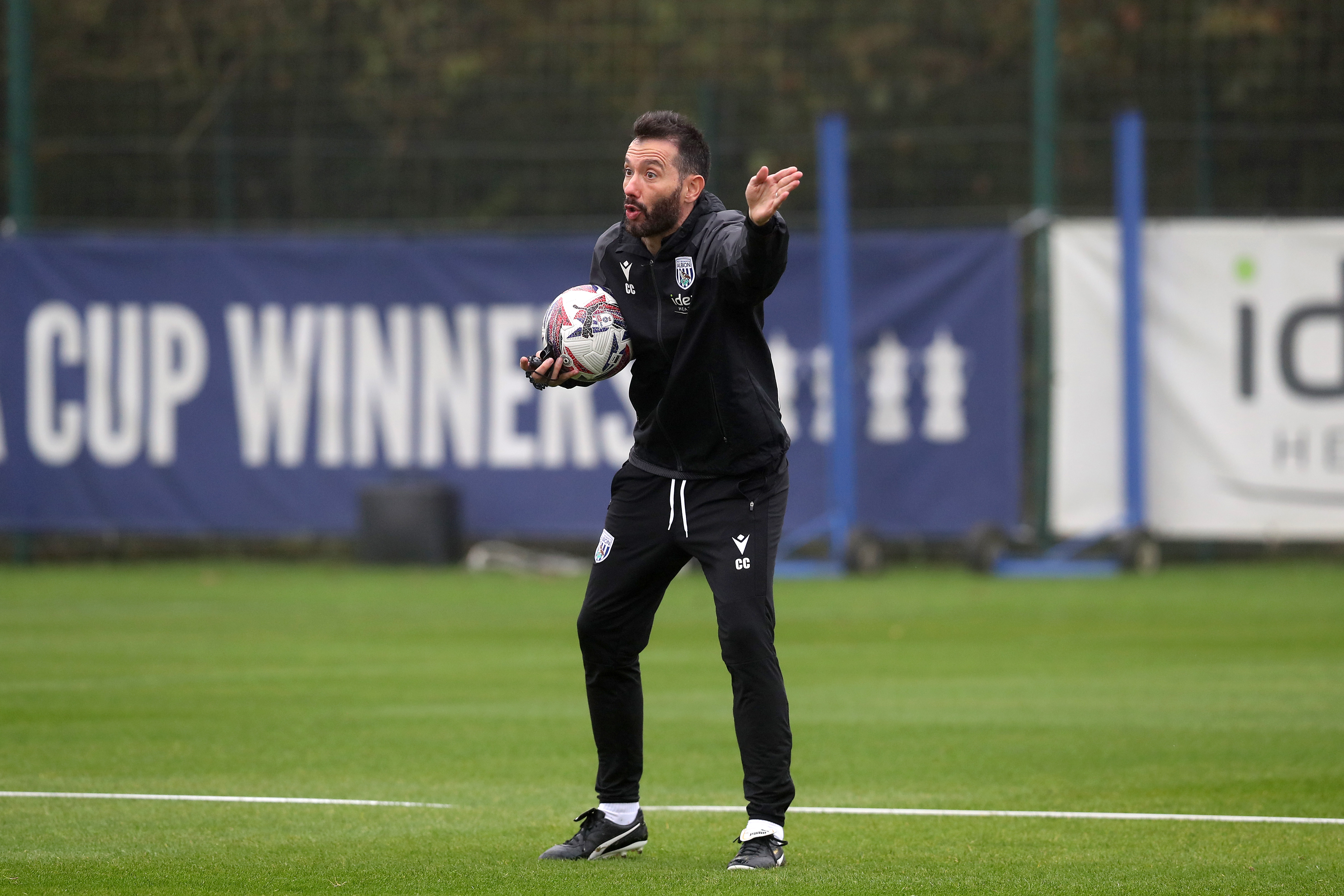 Carlos Corberán delivering information to his players on the training pitch while holding a ball