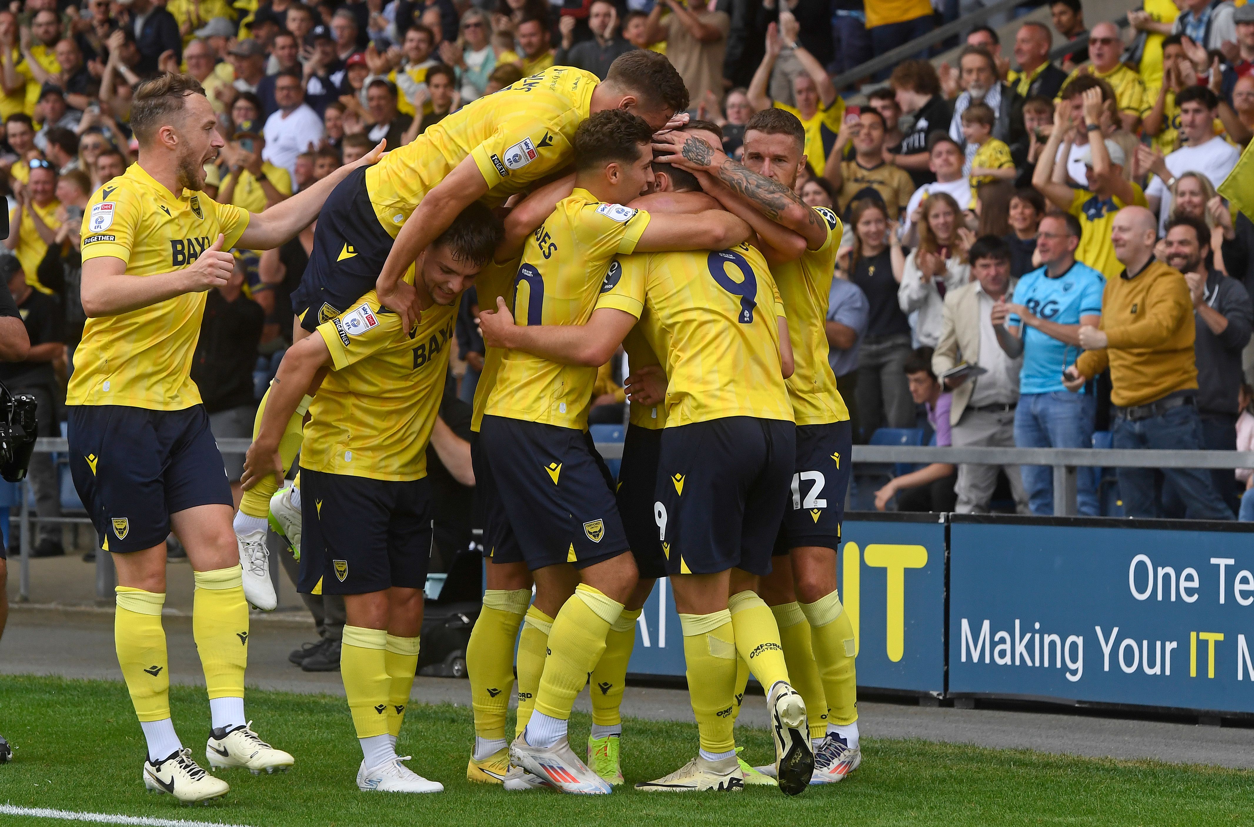 Several Oxford United players celebrate a goal scored at home to Norwich in the home kit 