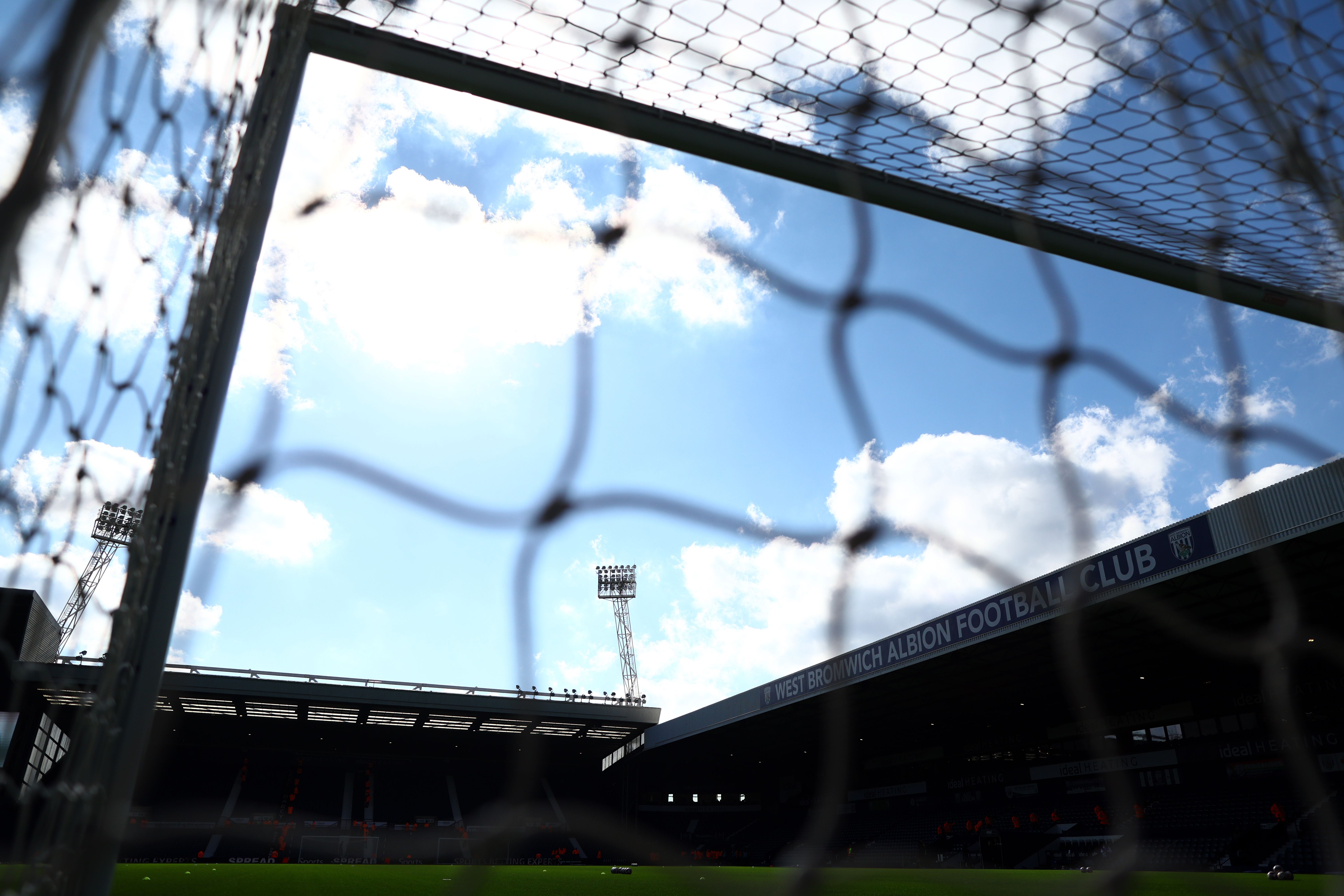 A general view of the top of the stands at The Hawthorns through a goal net with blue skies and clouds 