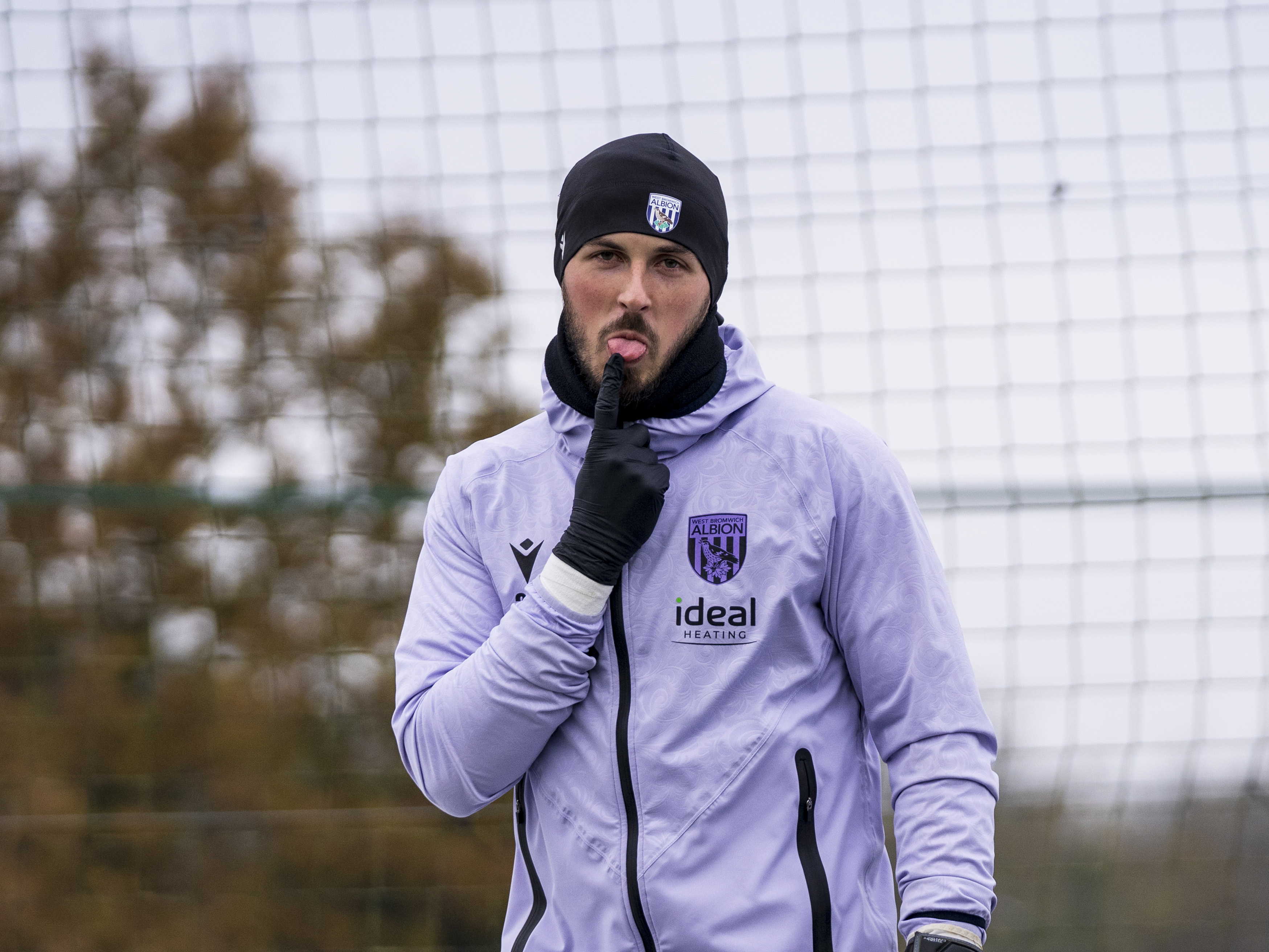 Joe Wildsmith sticking his tongue out at the camera while wearing a hat walking out to training 